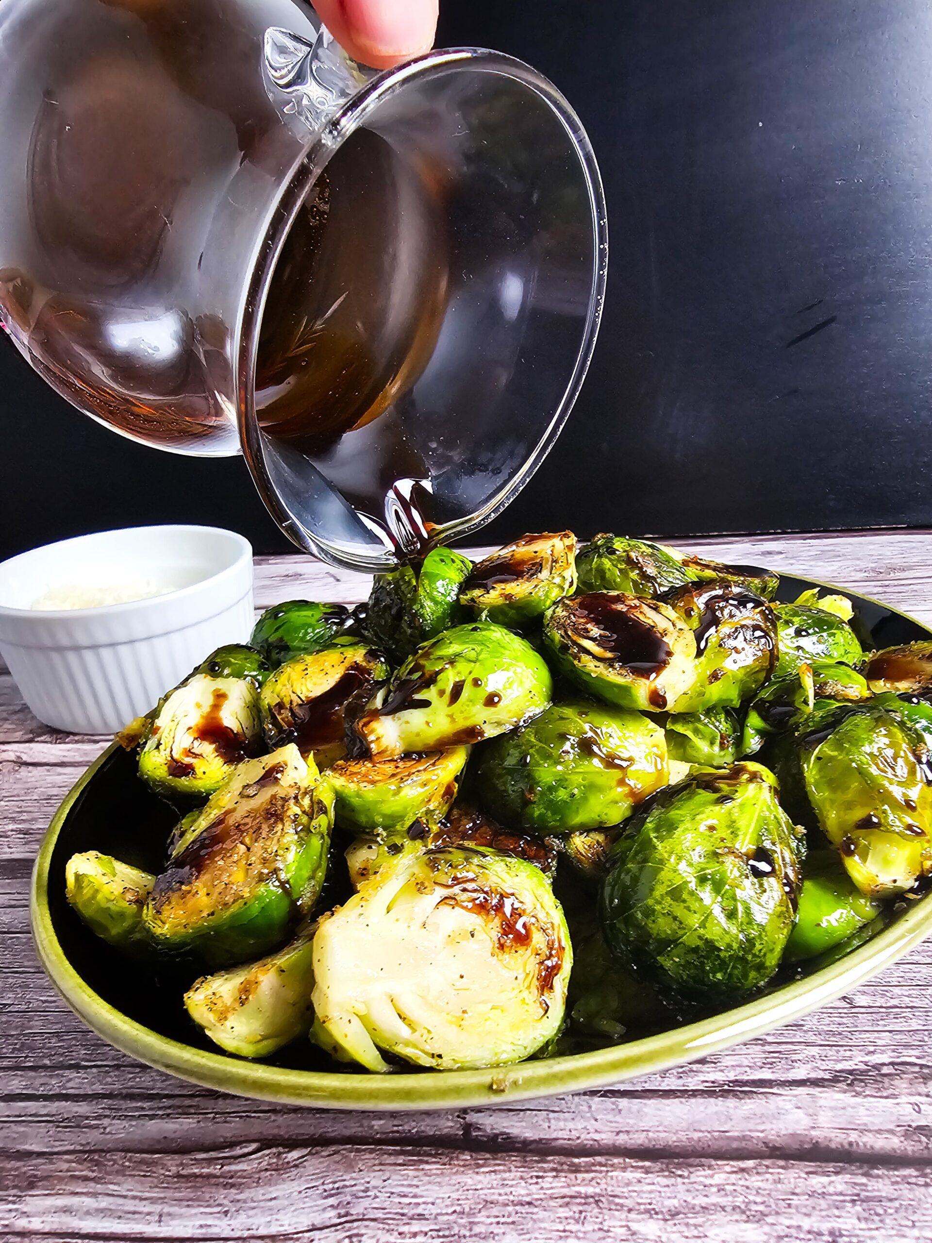 POUR THE REDUCED BALSAMIC GLAZE OVER THE ROASTED BRUSSELS SPROUTS