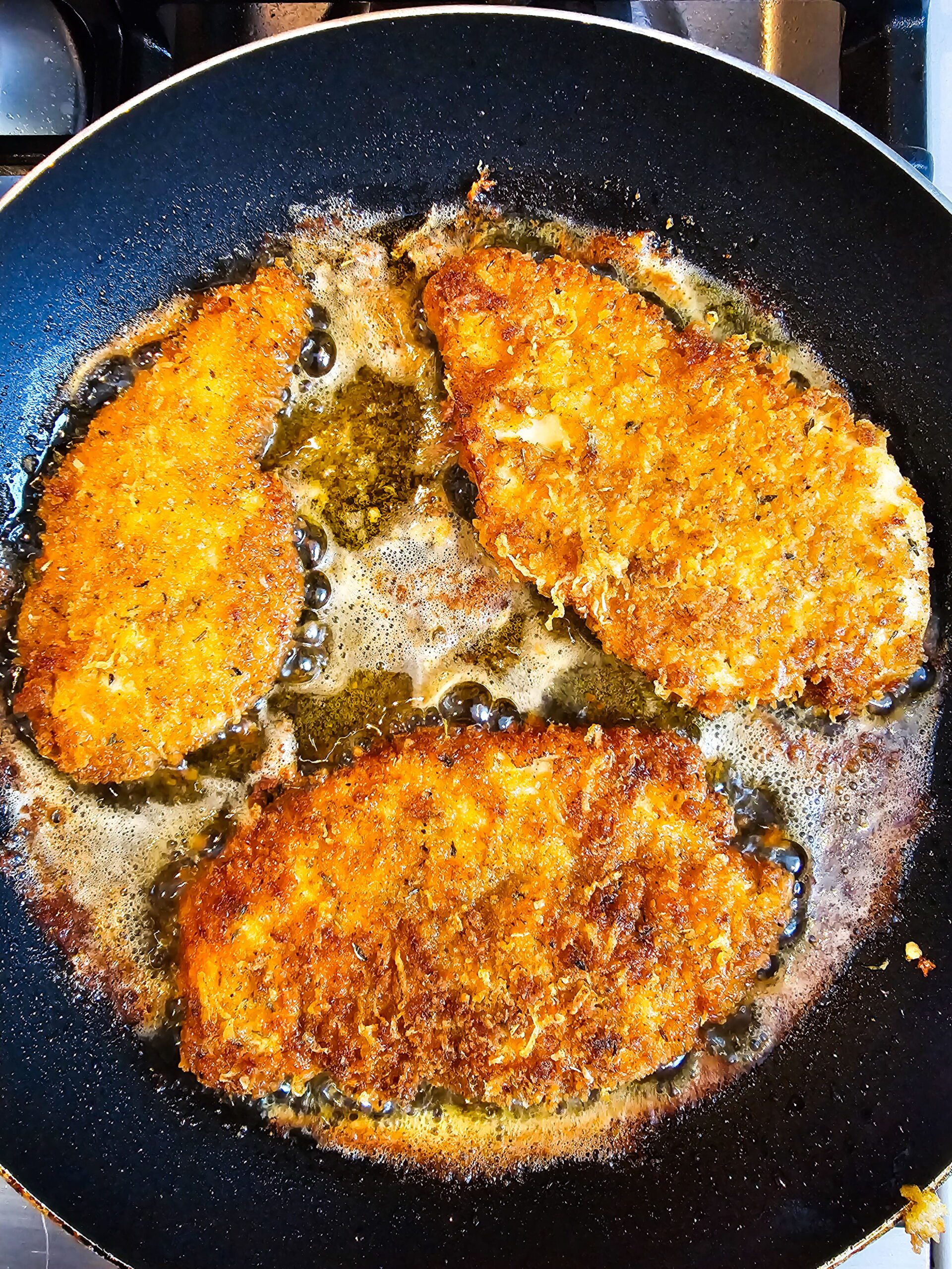Ranch parmesan chicken cutlets frying in a skillet until golden brown and crispy