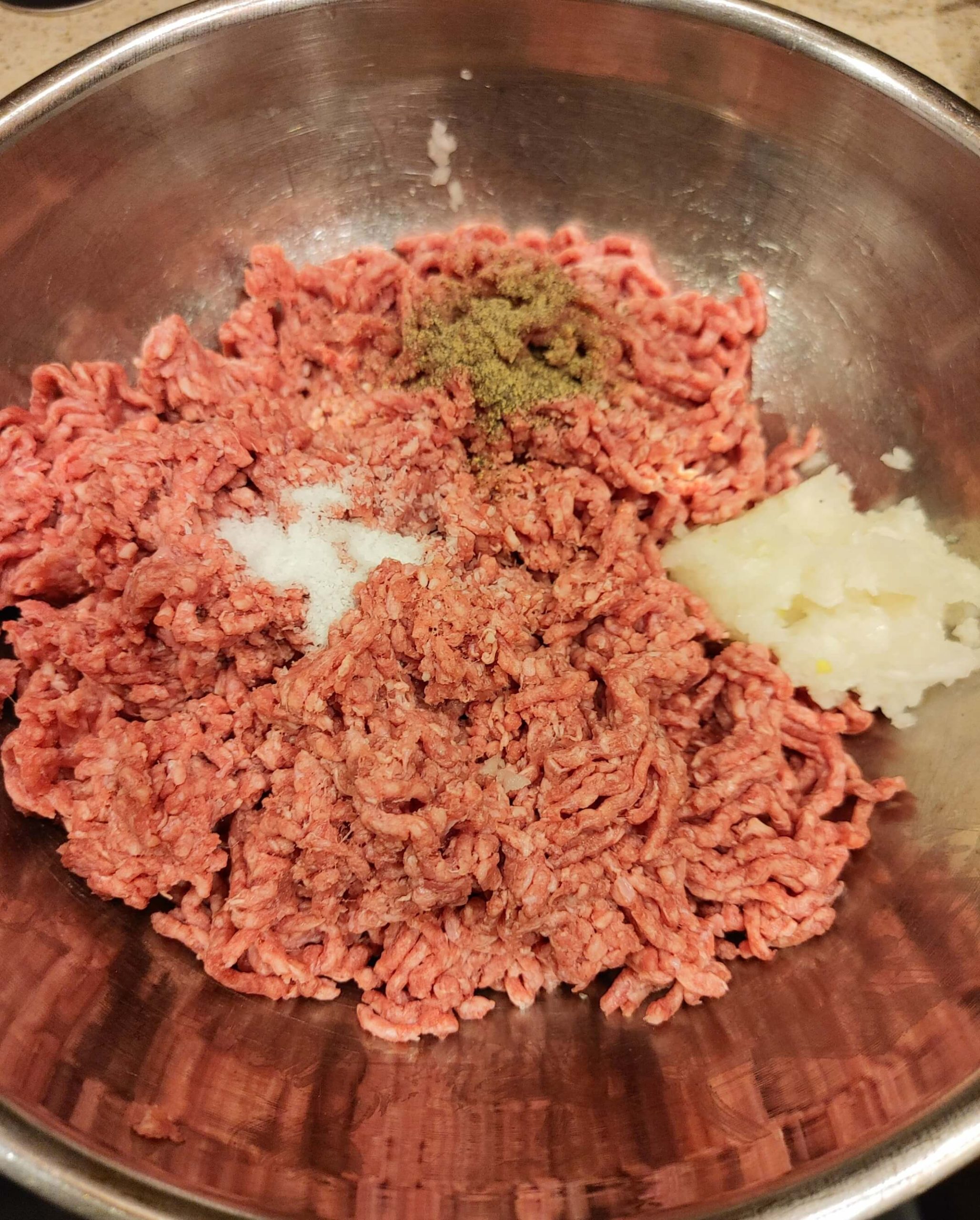 large metal bowl filled with ground beef and the spices