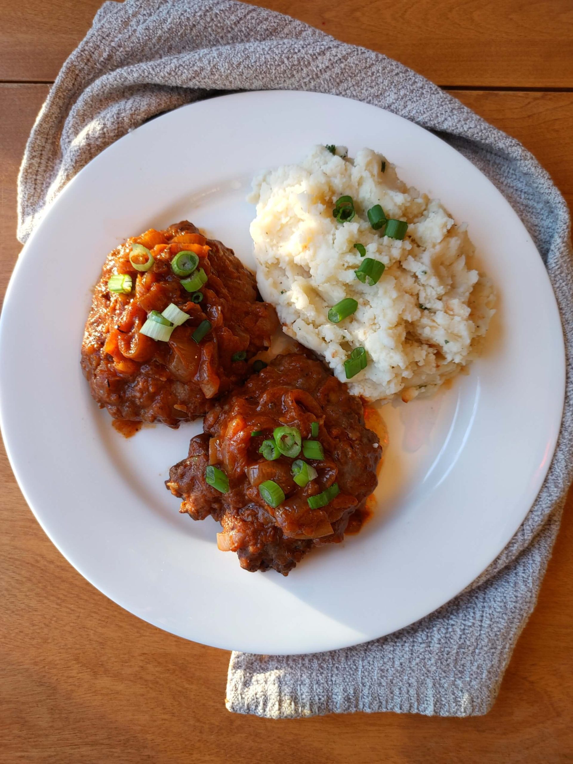 WHITE PLATE FULL OF FRENCH ONION SALISBURY STEAK AND MASHED POTATOES