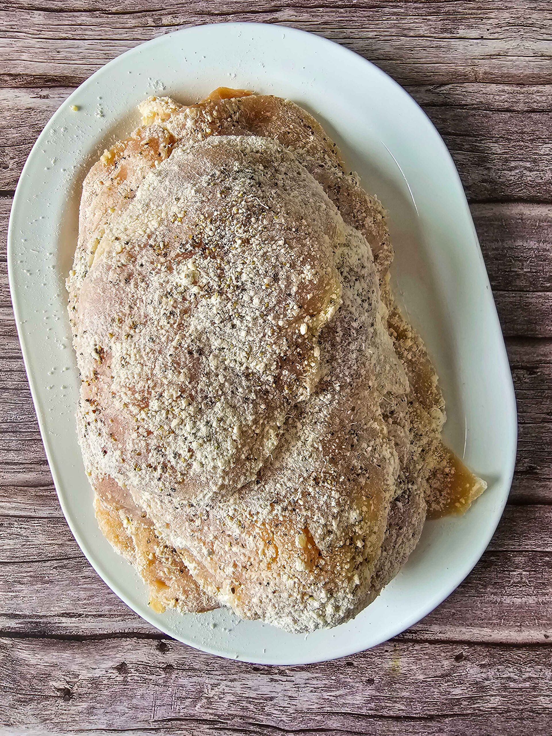 SEASON THE CHICKEN WITH SALT AND BLACK PEPPER AND DREDGE IN THE FLOUR PARMESAN MIXTURE