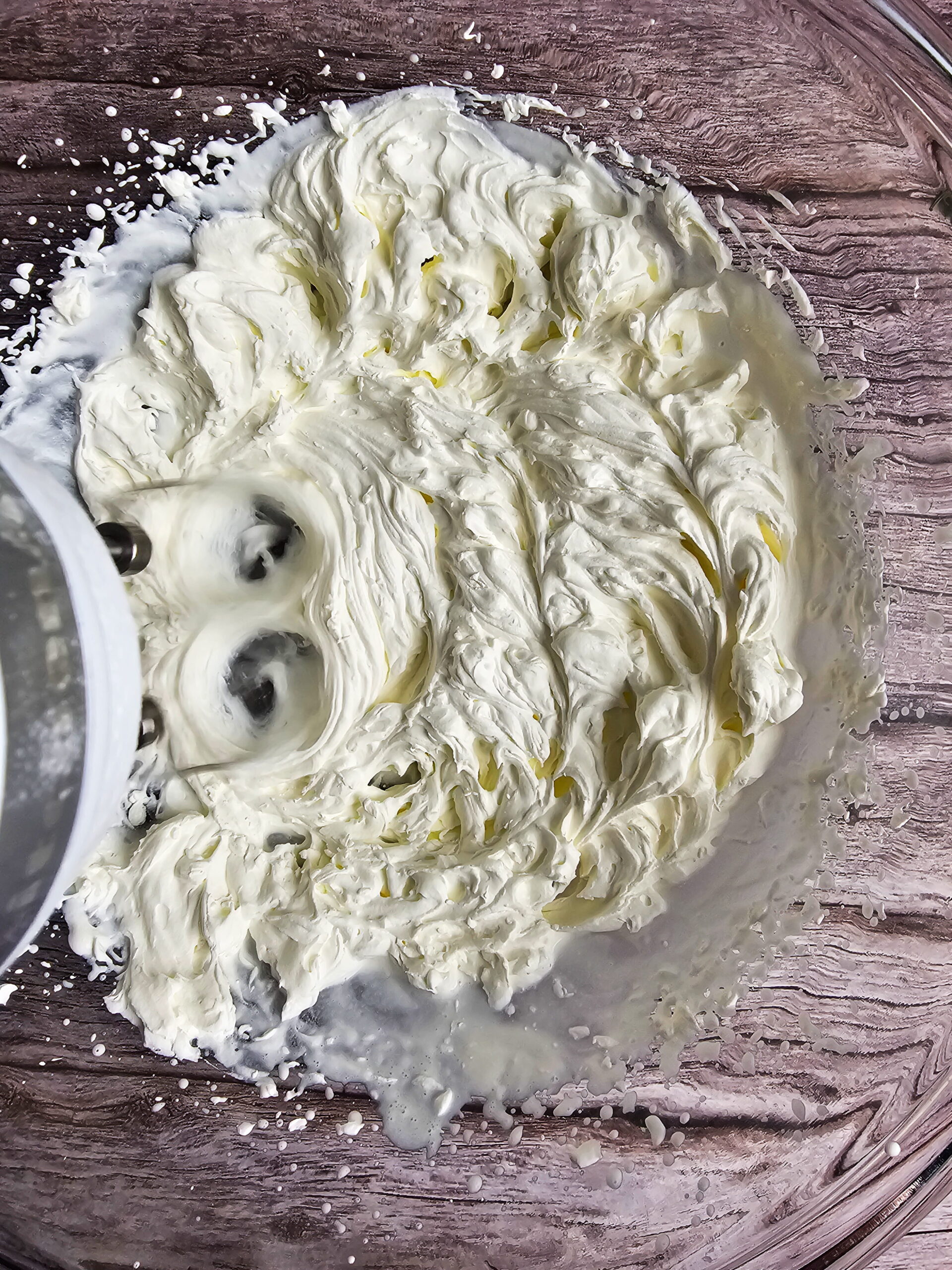 Heavy cream whipped to stiff peaks in a bowl with a hand mixer