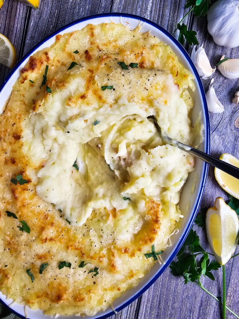 Chantilly mashed potatoes baked golden in a white casserole dish with cheese crust and fresh parsley
