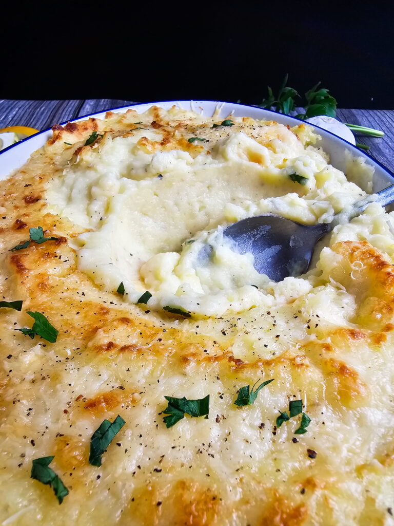 Chantilly mashed potatoes scooped onto a plate alongside roasted chicken and green beans