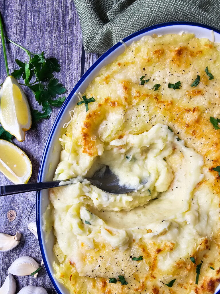 Chantilly mashed potato casserole topped with melted cheese served in a white baking dish
