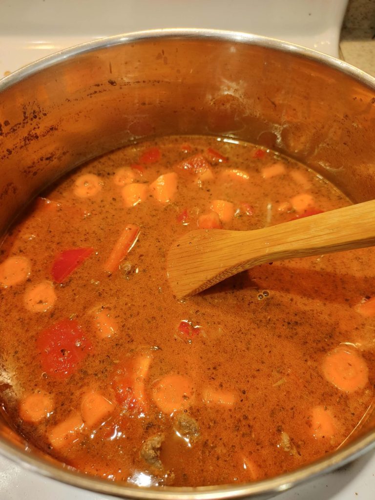 ADDING WATER TO THE BEEF, ONIONS, PAPRIKA AND GARLIC