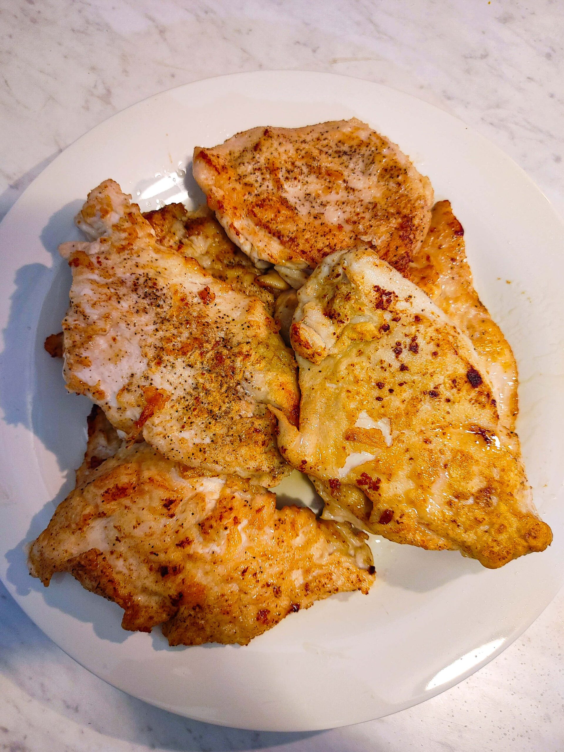 Chicken cutlets searing golden brown in olive oil and butter in a large skillet for Marry Me Chicken