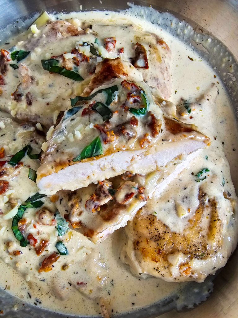 CHICKEN BREAST SLICED IN HALF TO SEE THE TEXTURE OF THE CHICKEN BATHING IN THE CREAMY SAUCE