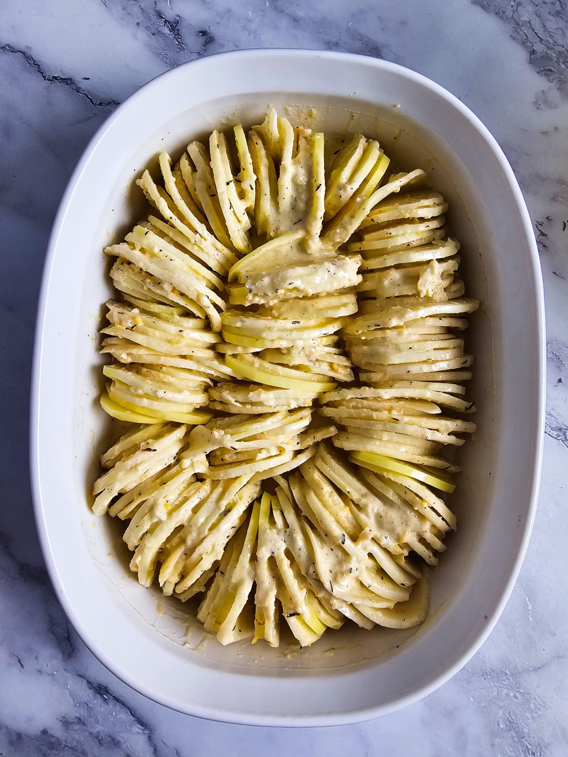 ARRANGE THE POTATO SLICES IN A SHALLOW OVAL BAKING DISH
