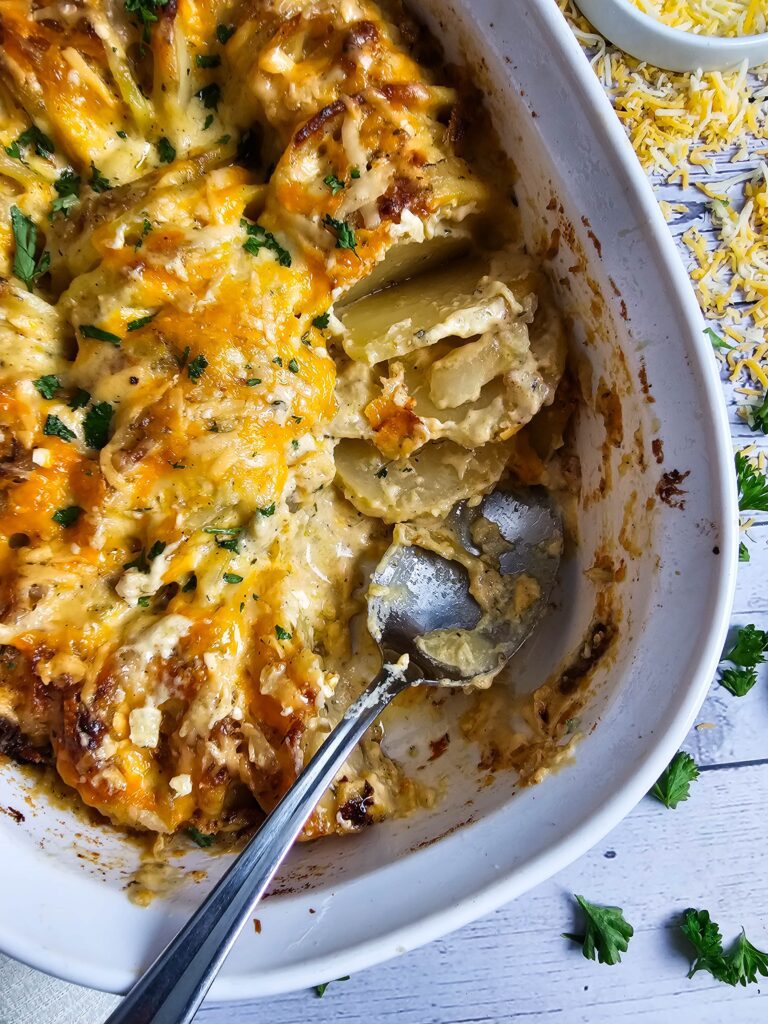OVAL CASSEROLE DISH WITH AU GRATIN POTATOES SCOOPED OUT AND SERVED
