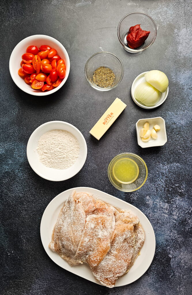Fresh ingredients for Italian chicken cutlets with tomato sauce including cherry tomatoes garlic and herbs