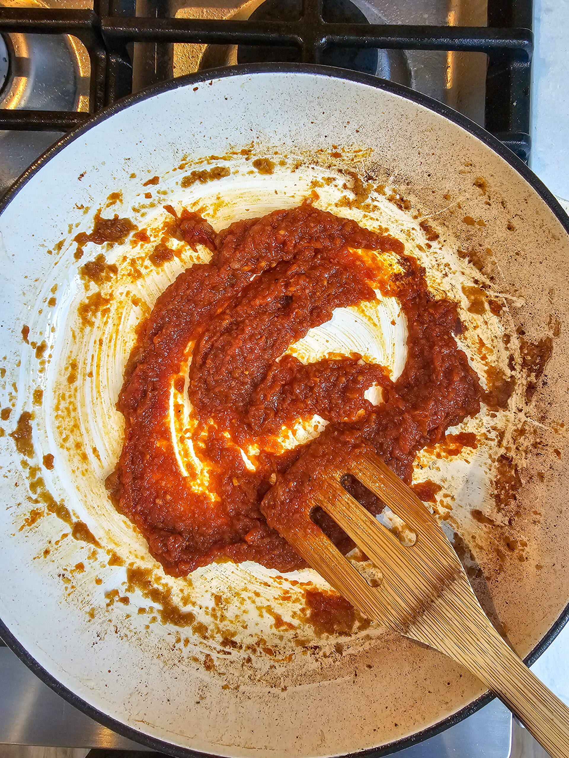 Tomato paste being cooked into sautéed onion and garlic to build a deep Italian tomato sauce
