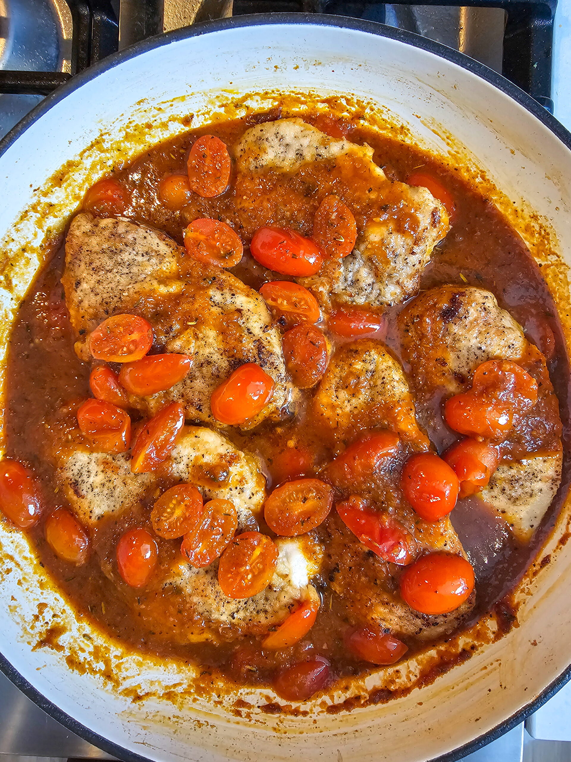 Chicken cutlets nestled back into cherry tomato pomodoro sauce finishing in the pan