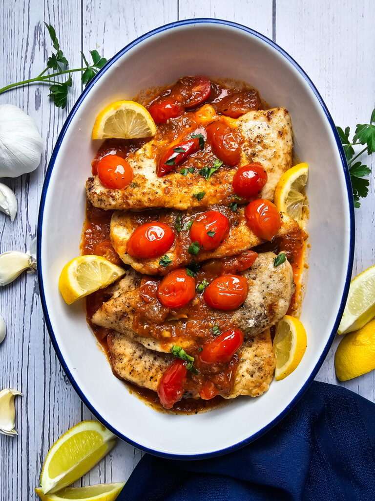 Italian chicken cutlets with tomato sauce in a skillet garnished with fresh basil