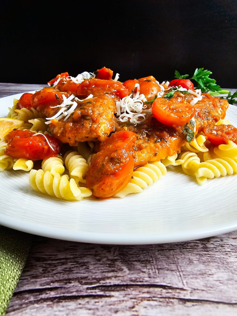 Italian chicken cutlets in tomato sauce served alongside a bed of pasta