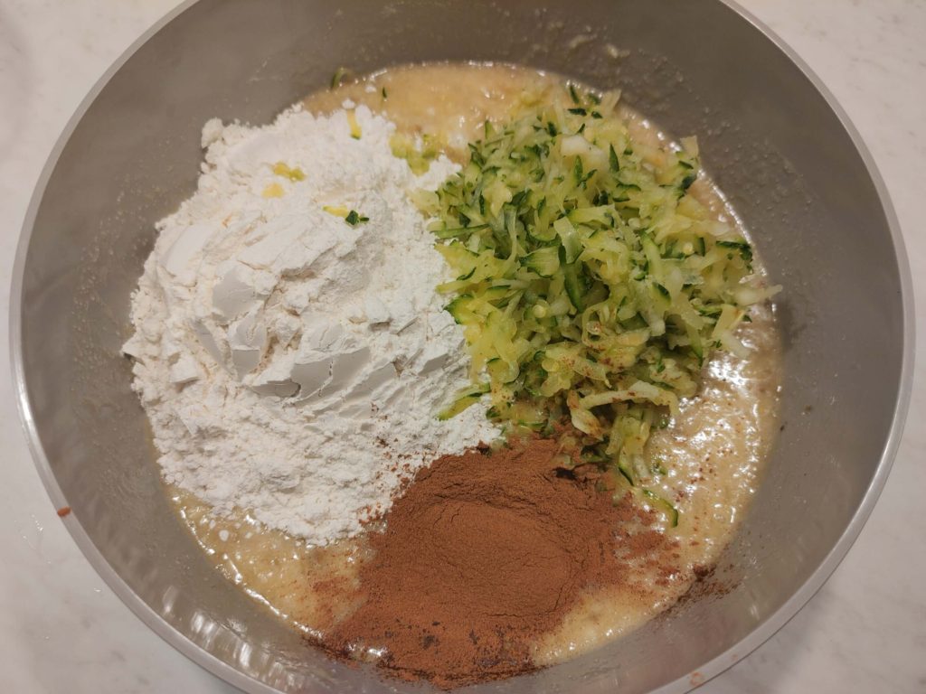 ADDING FLOUR, CINNAMON, AND ZUCCHINI