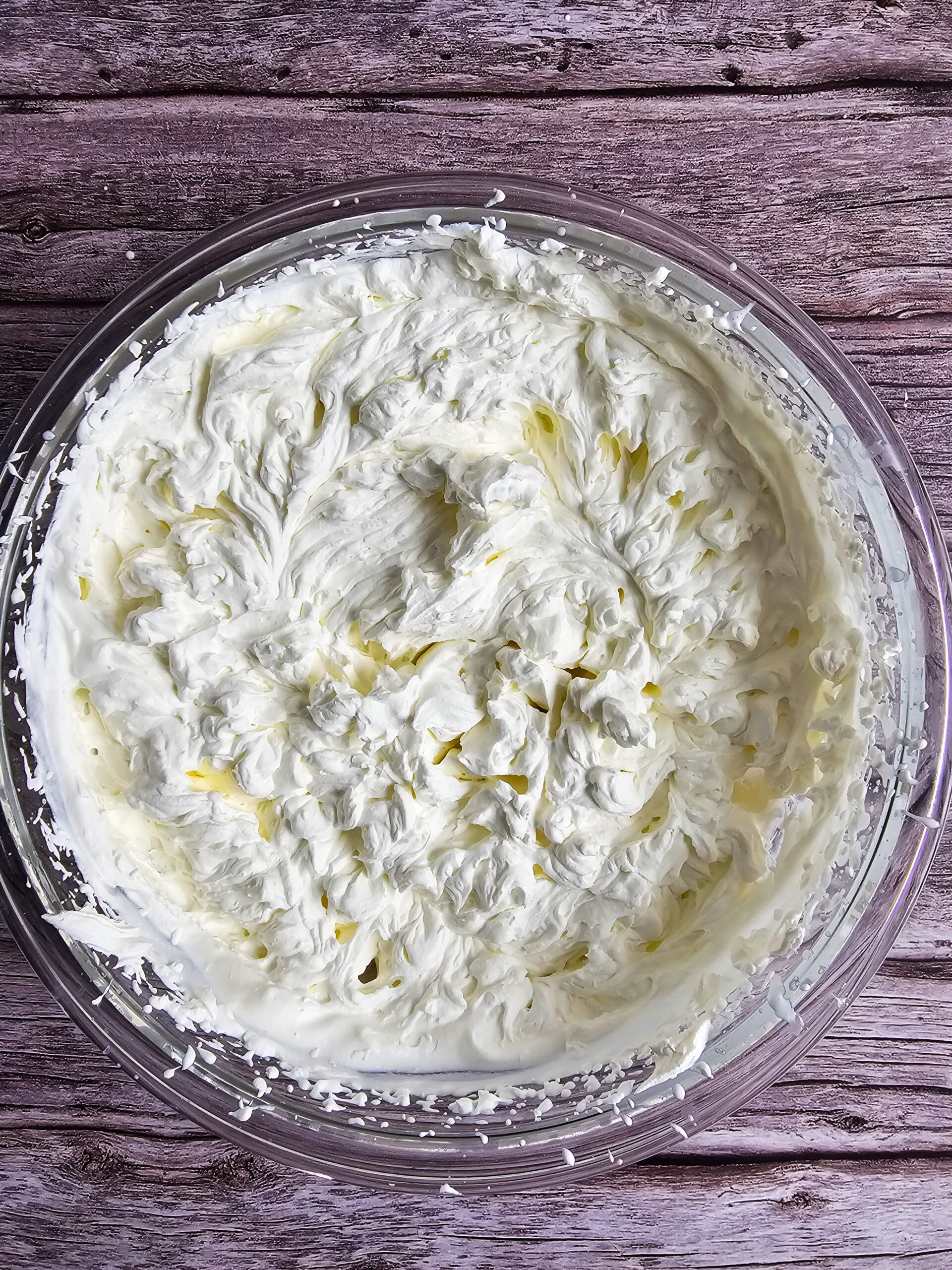 Heavy whipping cream beaten to stiff peaks in a chilled mixing bowl for eclair cake filling
