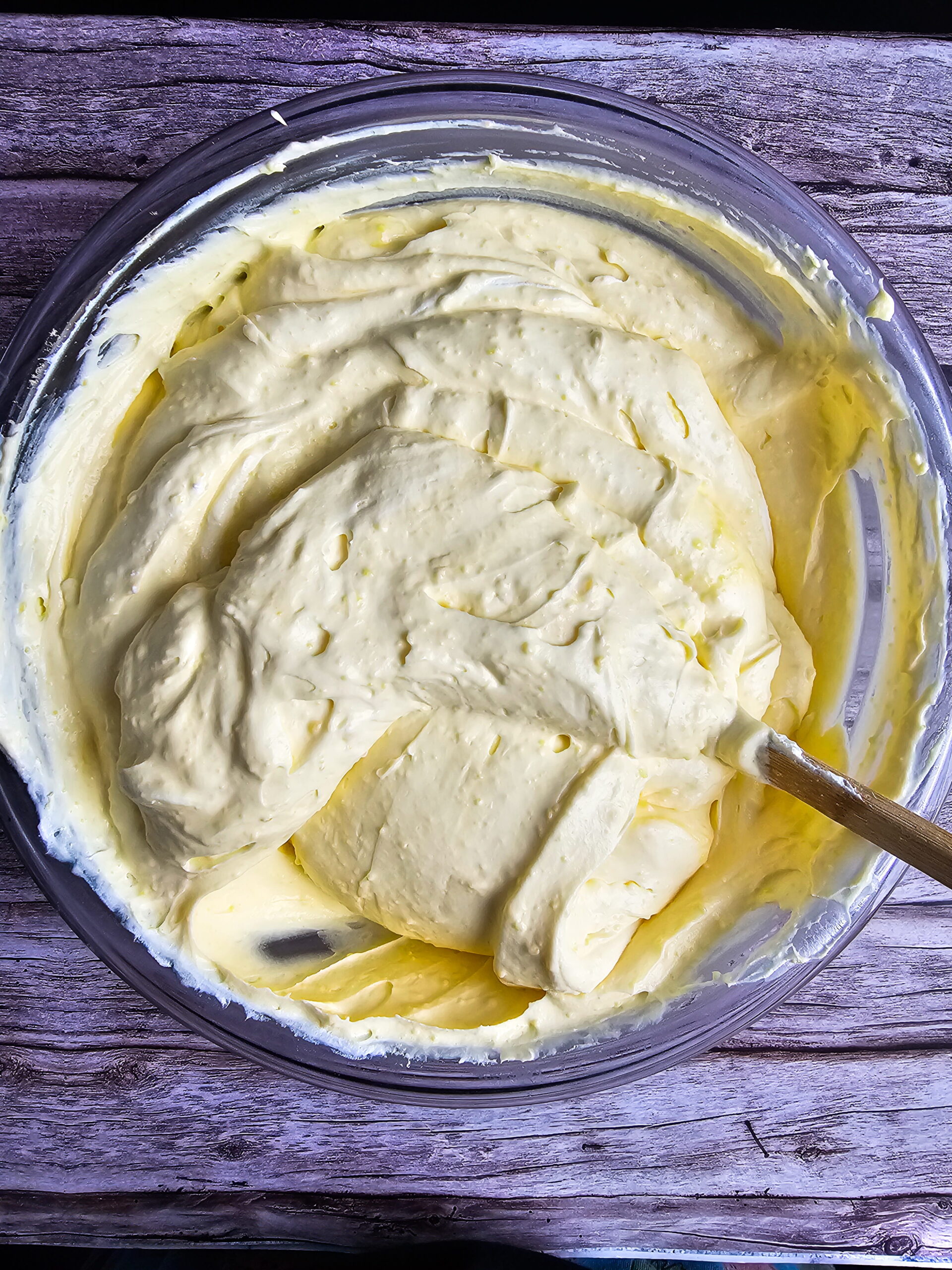 Whipped cream being folded into vanilla pudding filling for triple-layer eclair cake