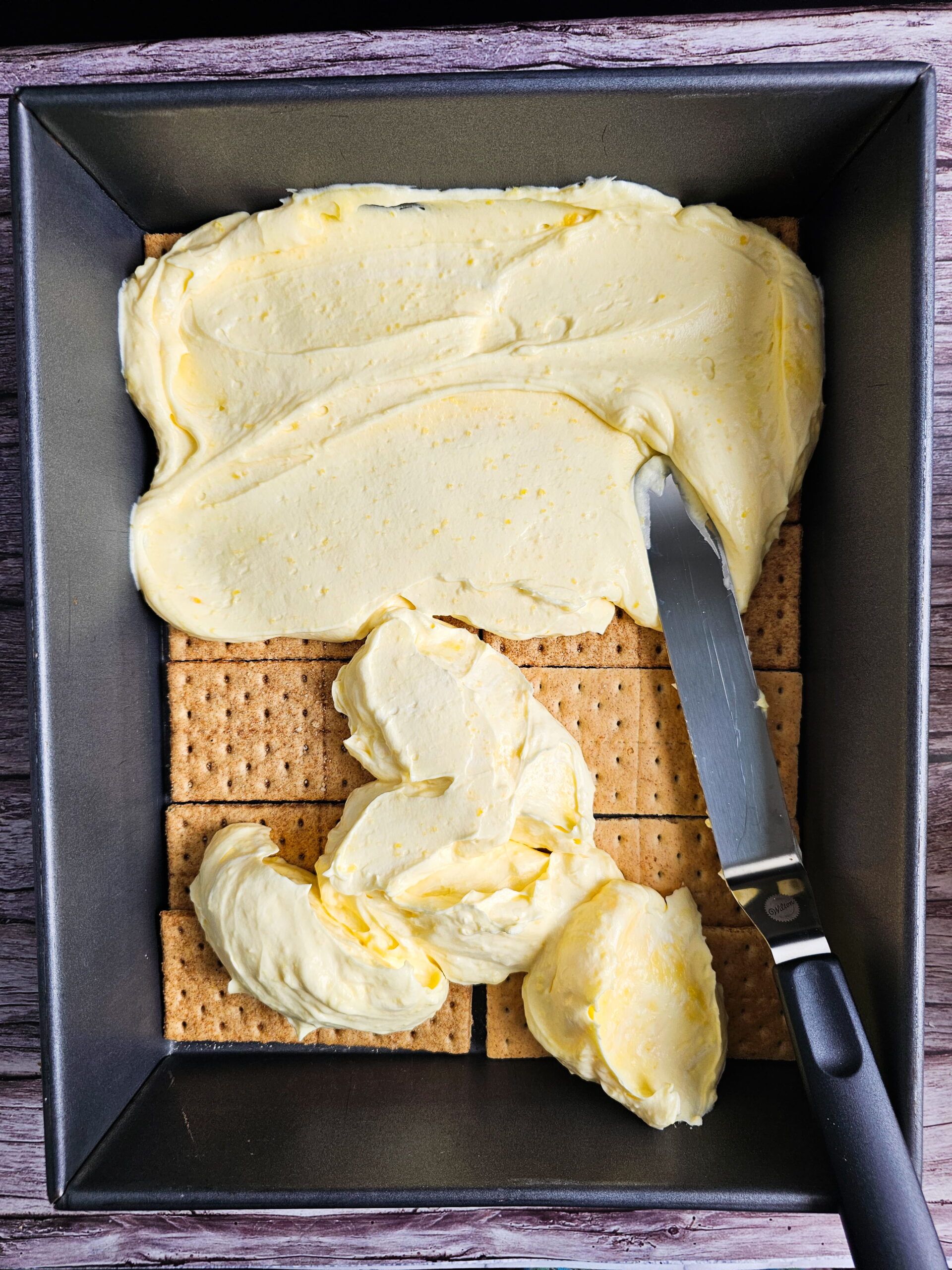 Graham cracker layers being built in a 14x11 lasagna pan for large-batch eclair cake