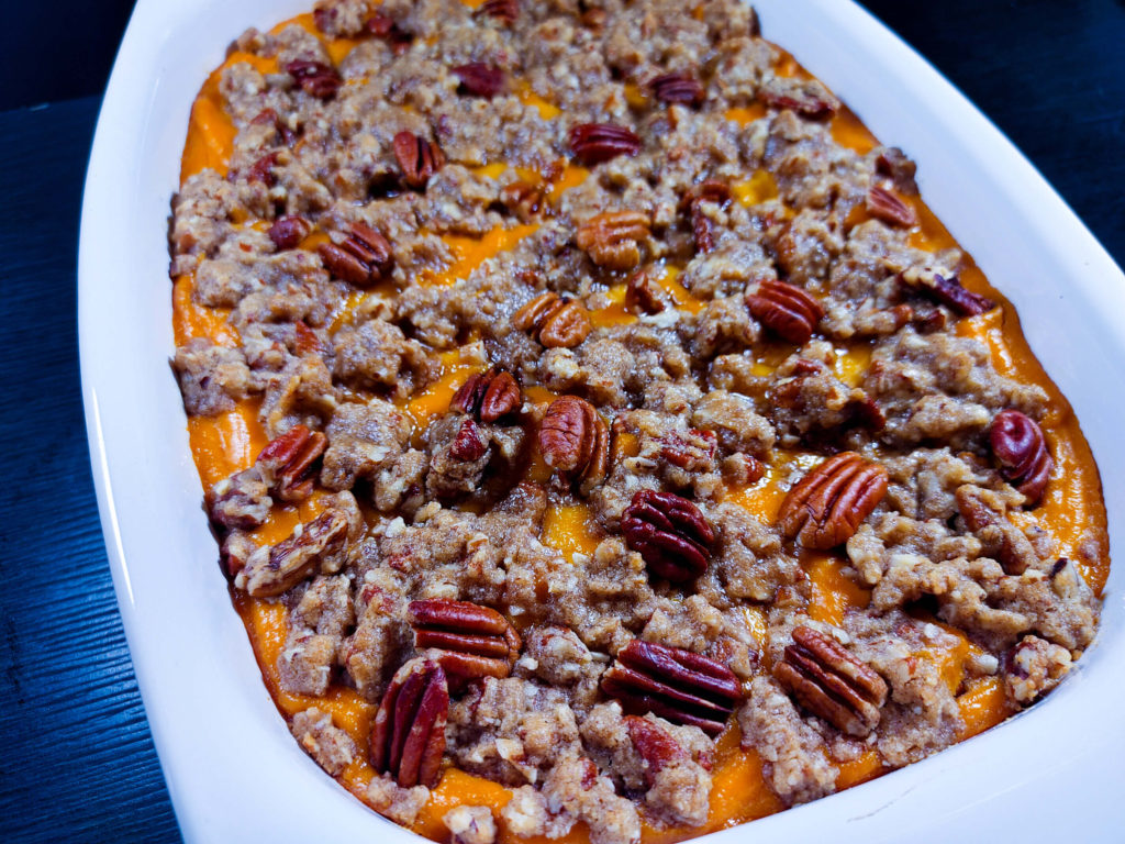 adding the pecan topping to the sweet potato