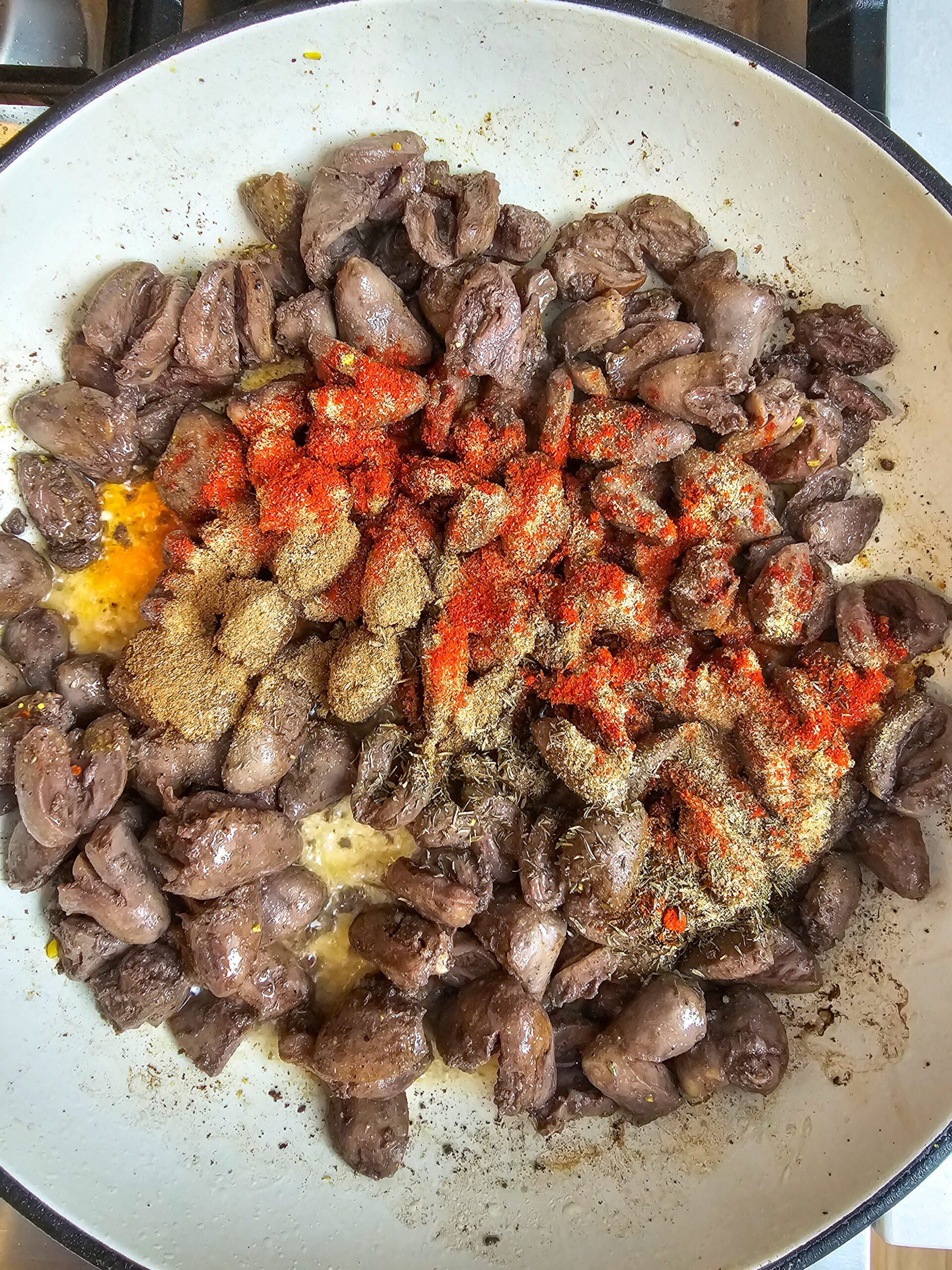 sauteed chicken hearts golden and crispy in skillet with seasonings after adding avocado oil and spices