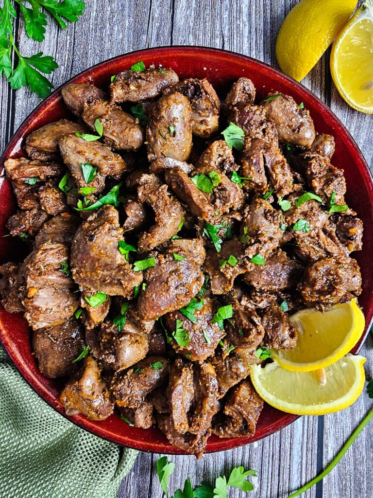 sauteed chicken hearts crispy and golden in a skillet garnished with fresh parsley