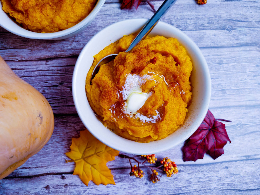 CREAMY BUTTERNUT SQUASH IN A BOWL TOPPED WITH BUTTER