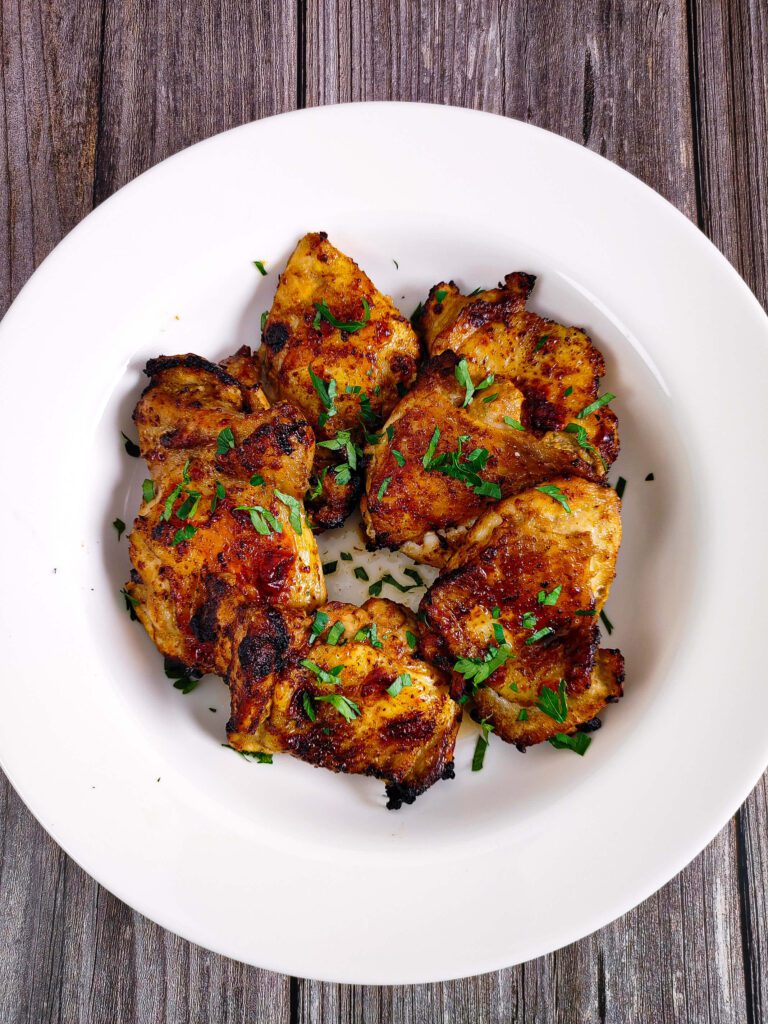 crispy air fryer marinated chicken thighs bone-in skin-on, golden brown on white plate