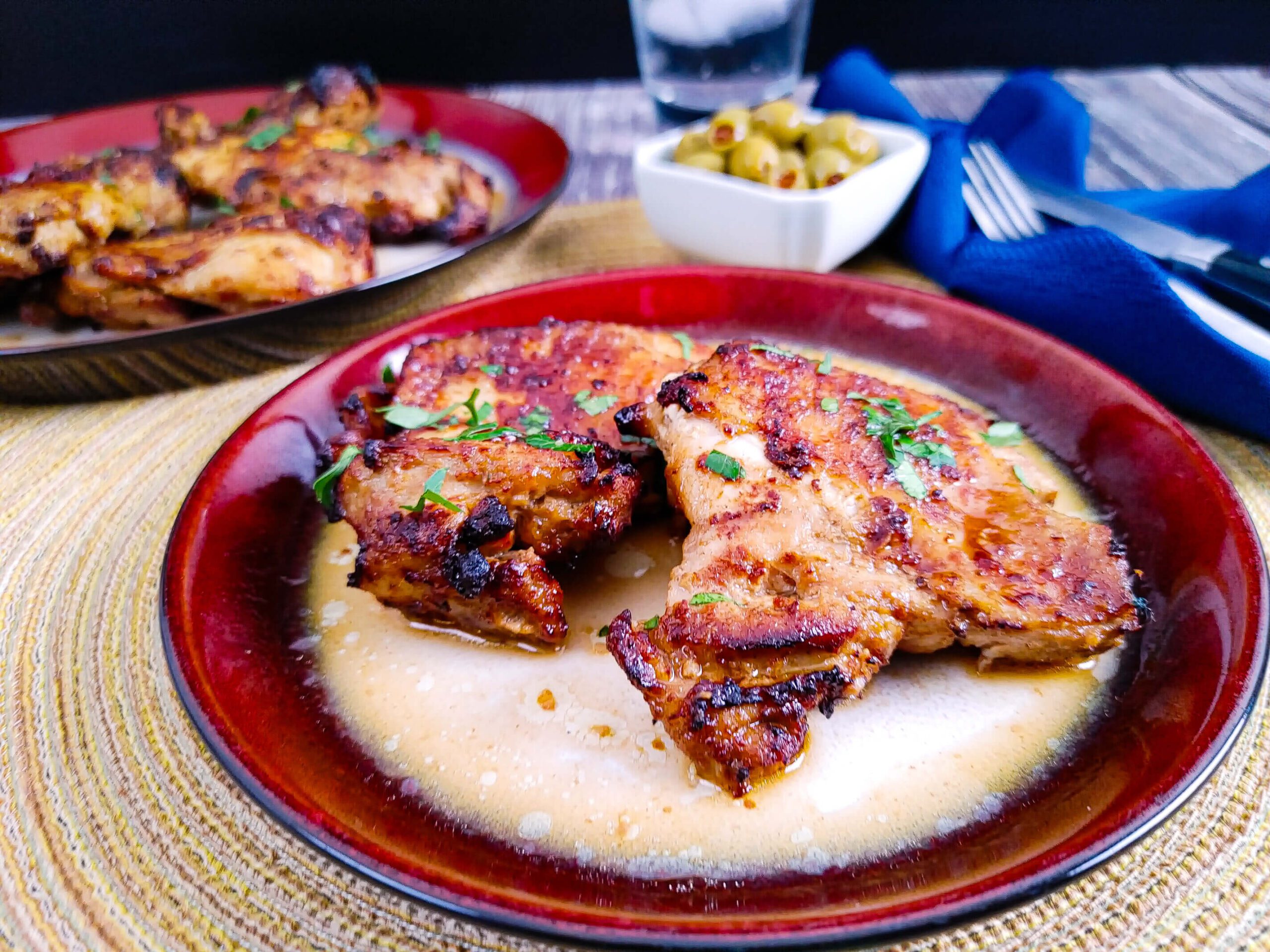 brushing reserved marinade glaze onto crispy bone-in air fryer chicken thighs after cooking
