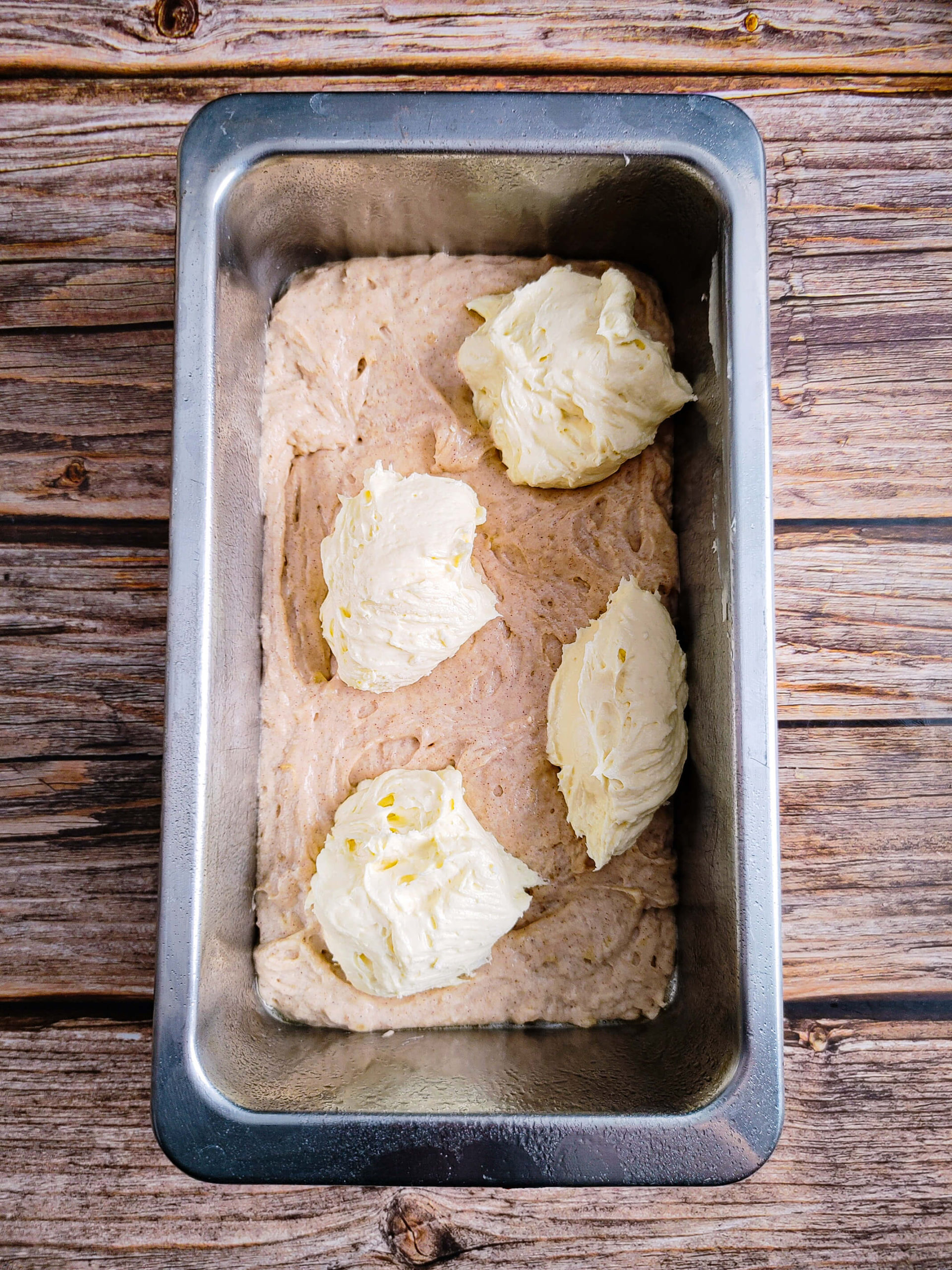 ADD HALF THE BANANA BREAD BATTER AND DOLLOP THE CREAM CHEESE ON TOP