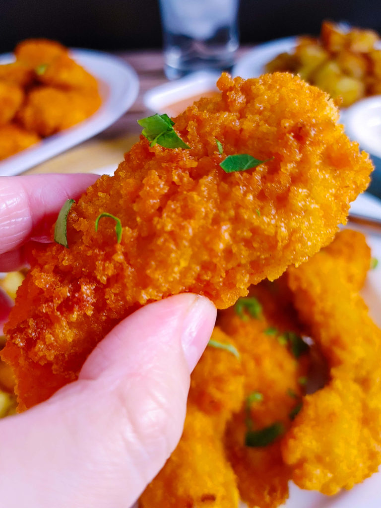 UPCLOSE PHOTO OF CRISPY AIR FRYER BUFFALO CHICKEN TENDER IN HAND