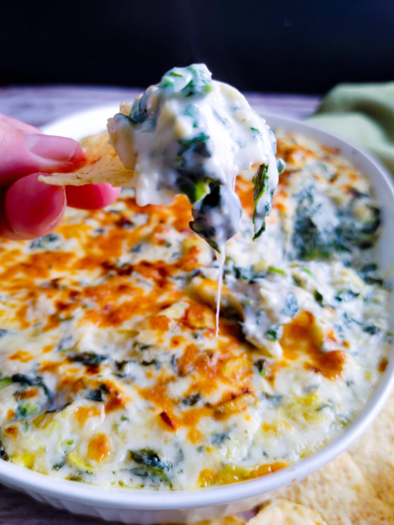 DIPPING TORTILLA CHIPS IN SPINACH ARTICHOKE DIP