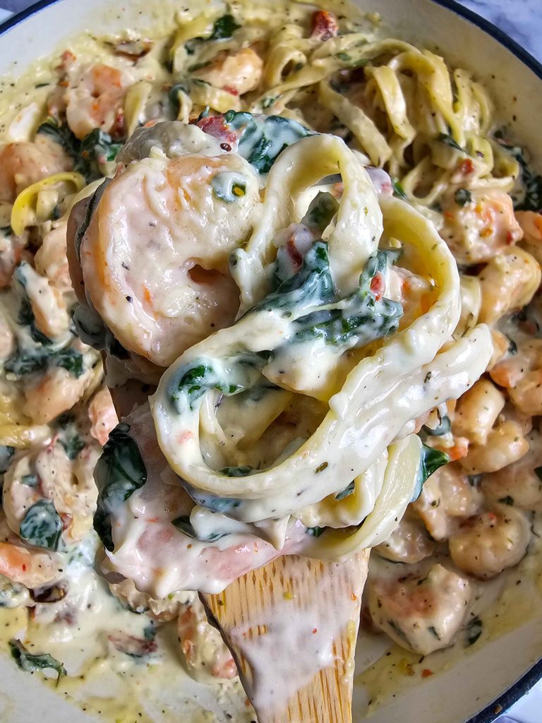 UP CLOSR ON A WOODEN SPOON CREAMY TUSCAN SHRIMP PASTA