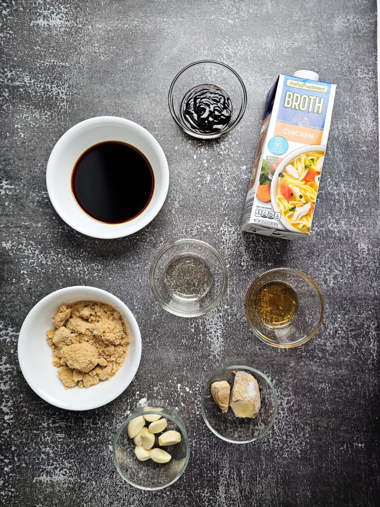 Mongolian chicken sauce ingredients measured in bowls with soy sauce brown sugar broth hoisin sesame oil and rice vinegar.