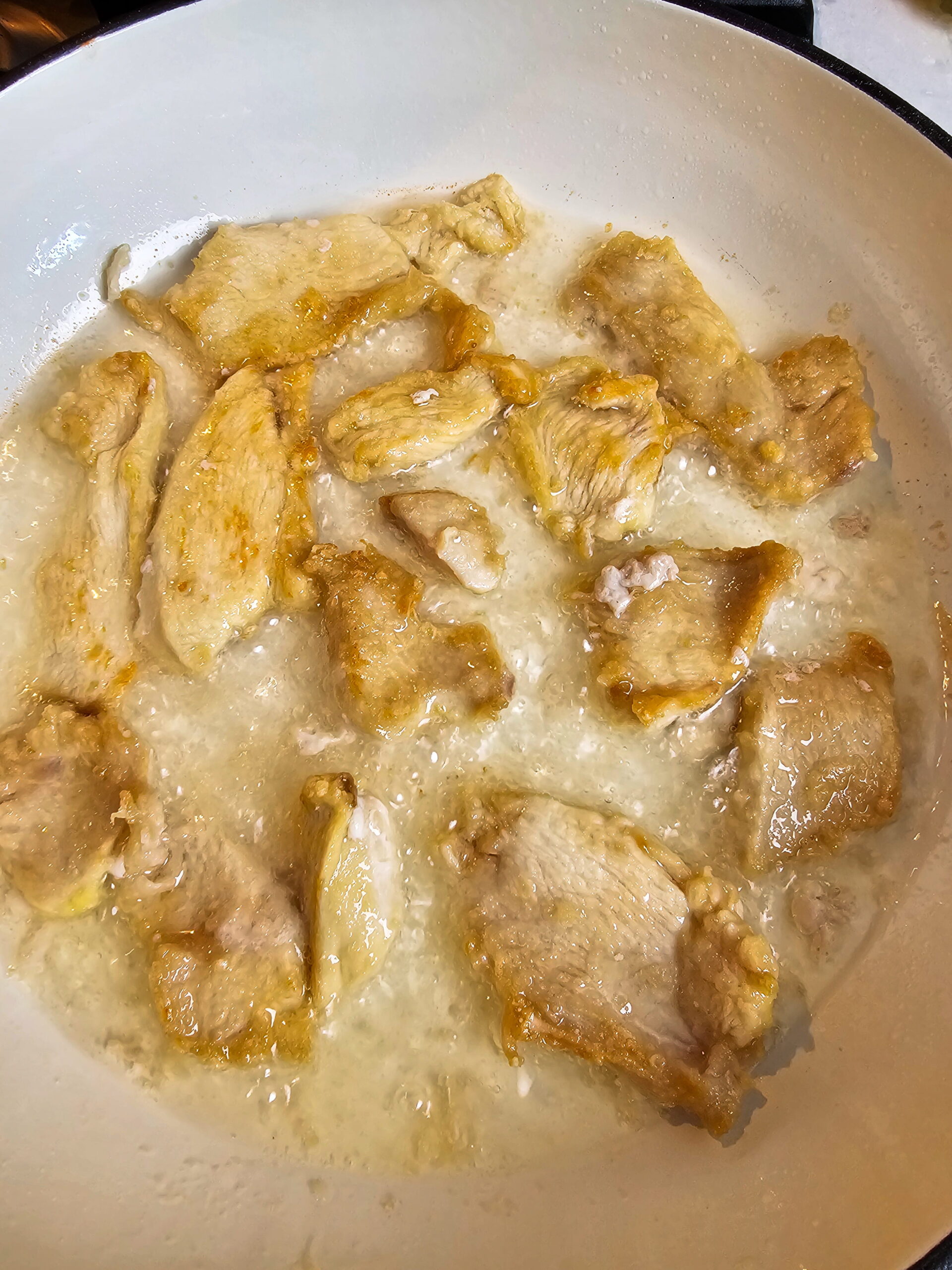 Seared chicken pieces cooking in skillet until golden brown and crispy for Mongolian chicken.