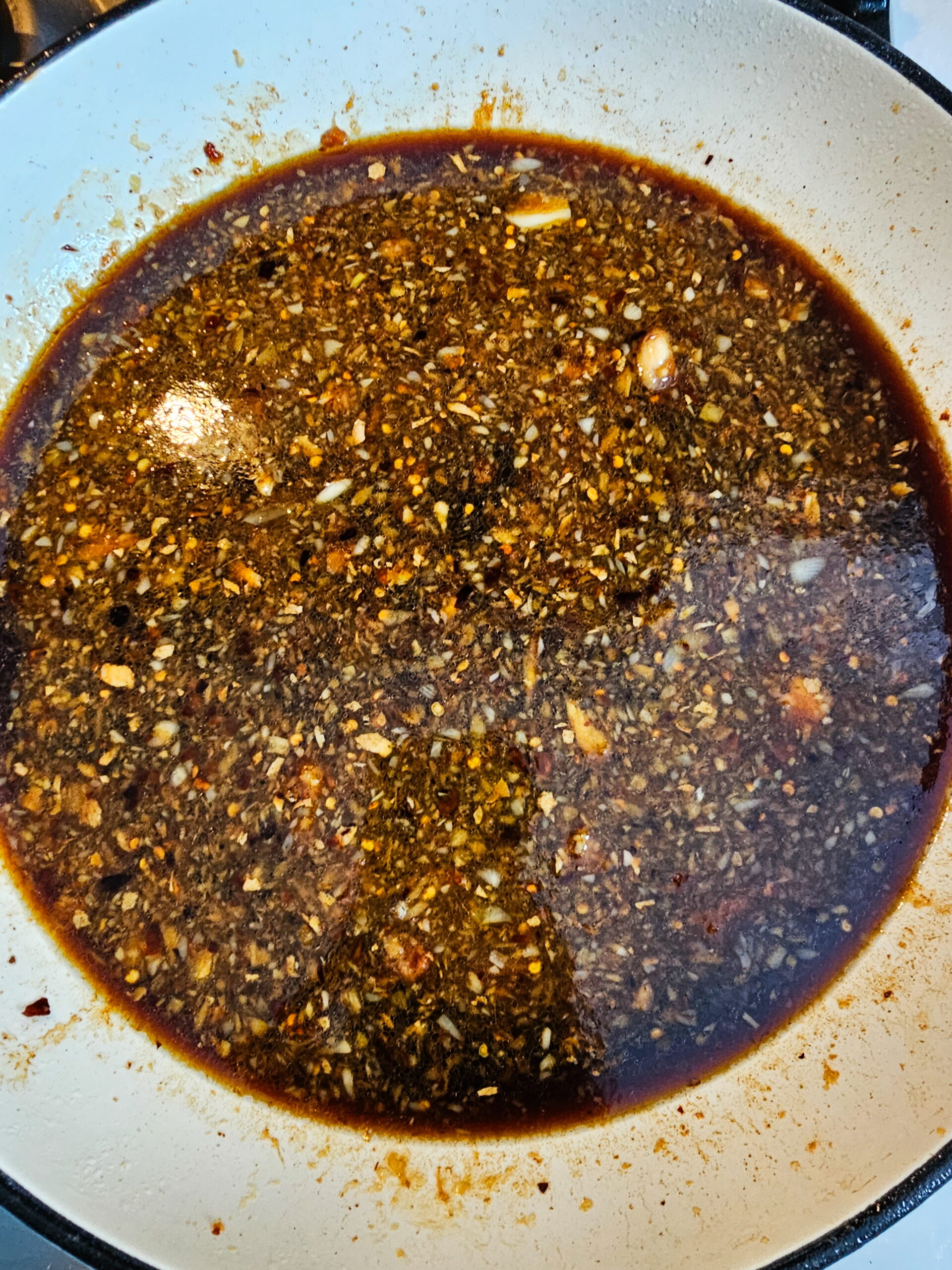 Mongolian chicken sauce simmering in skillet until thick glossy and sticky