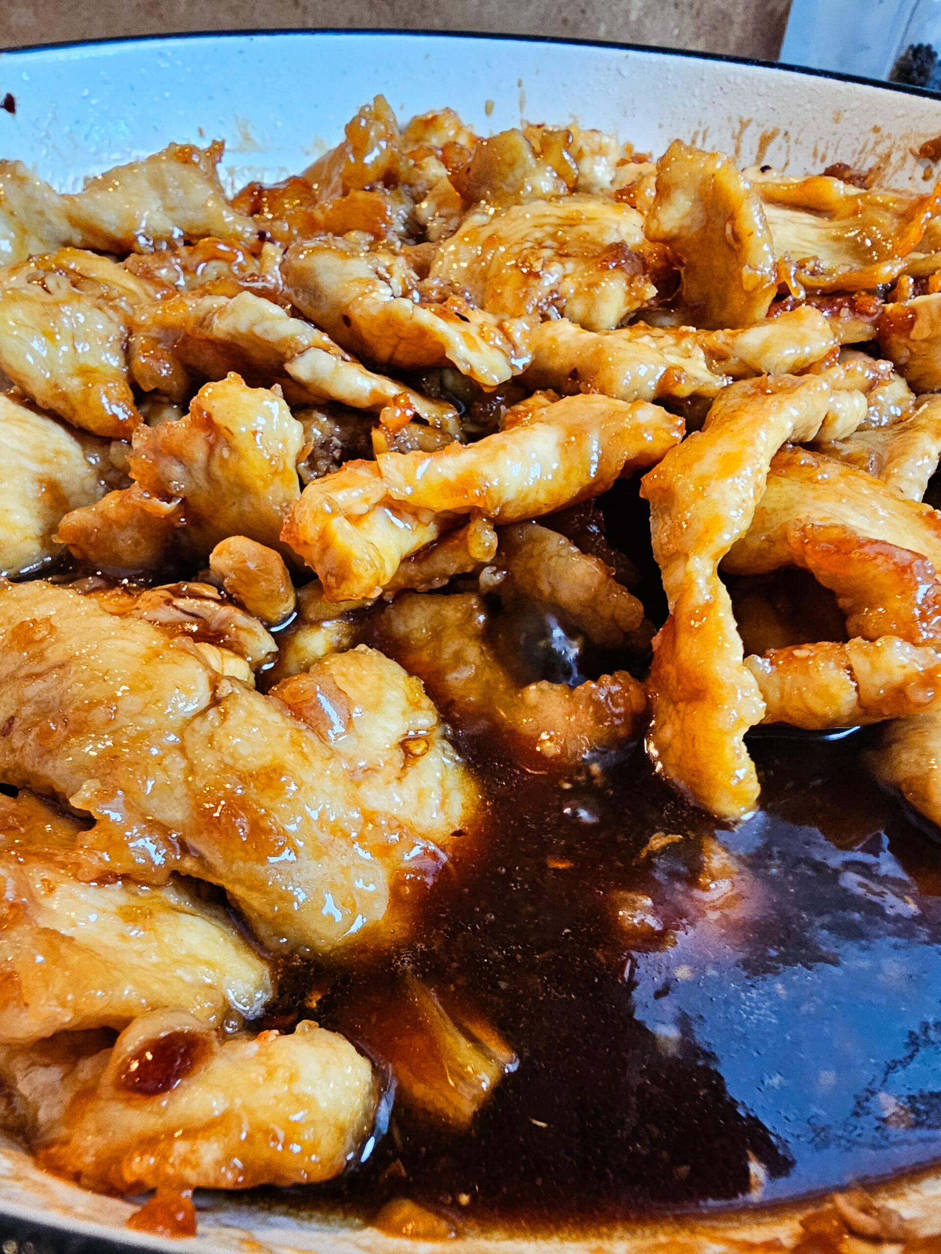 Crispy chicken tossed in rich Mongolian sauce coating every piece in skillet.