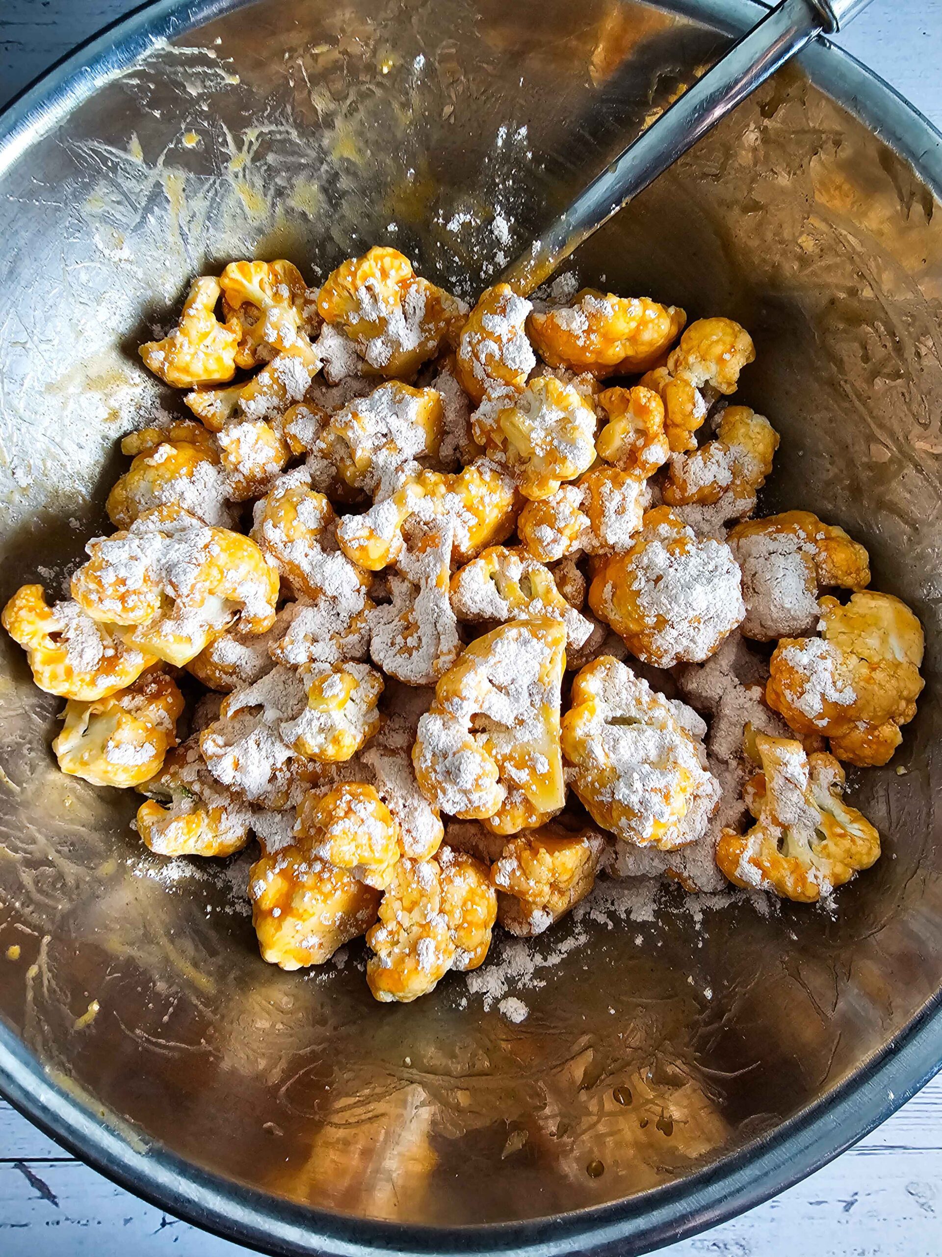 COAT THE CAULIFLOWER IN THE BUFFALO SAUCE AND SPRINKLE THE FLOUR MIXTURE