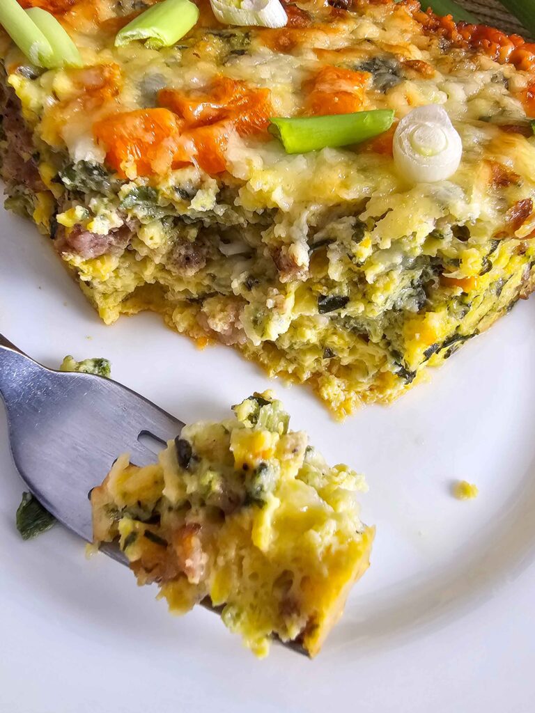 COTTAGE CHEESE AND EGG BREAKFAST CASSEROLE UP CLOSE ON A FORK SERVED ON A PLATE