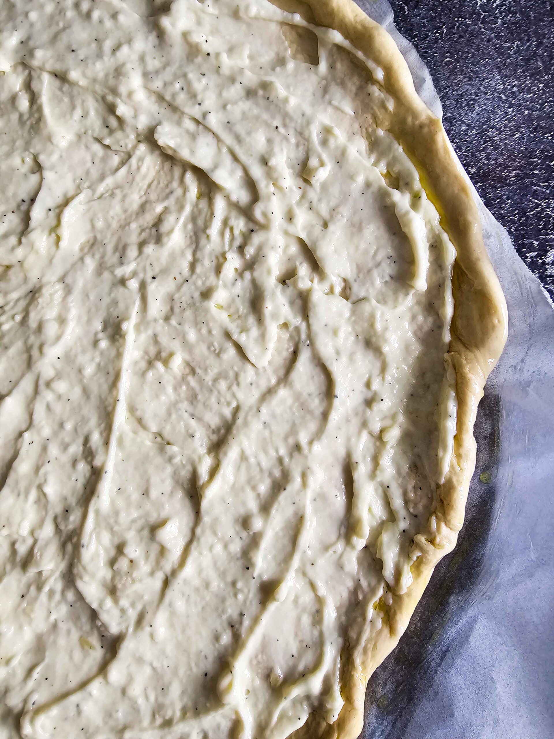 ADDING THE CREAMY WHITE GARLIC PIZZA SAUCE TO PIZZA DOUGH