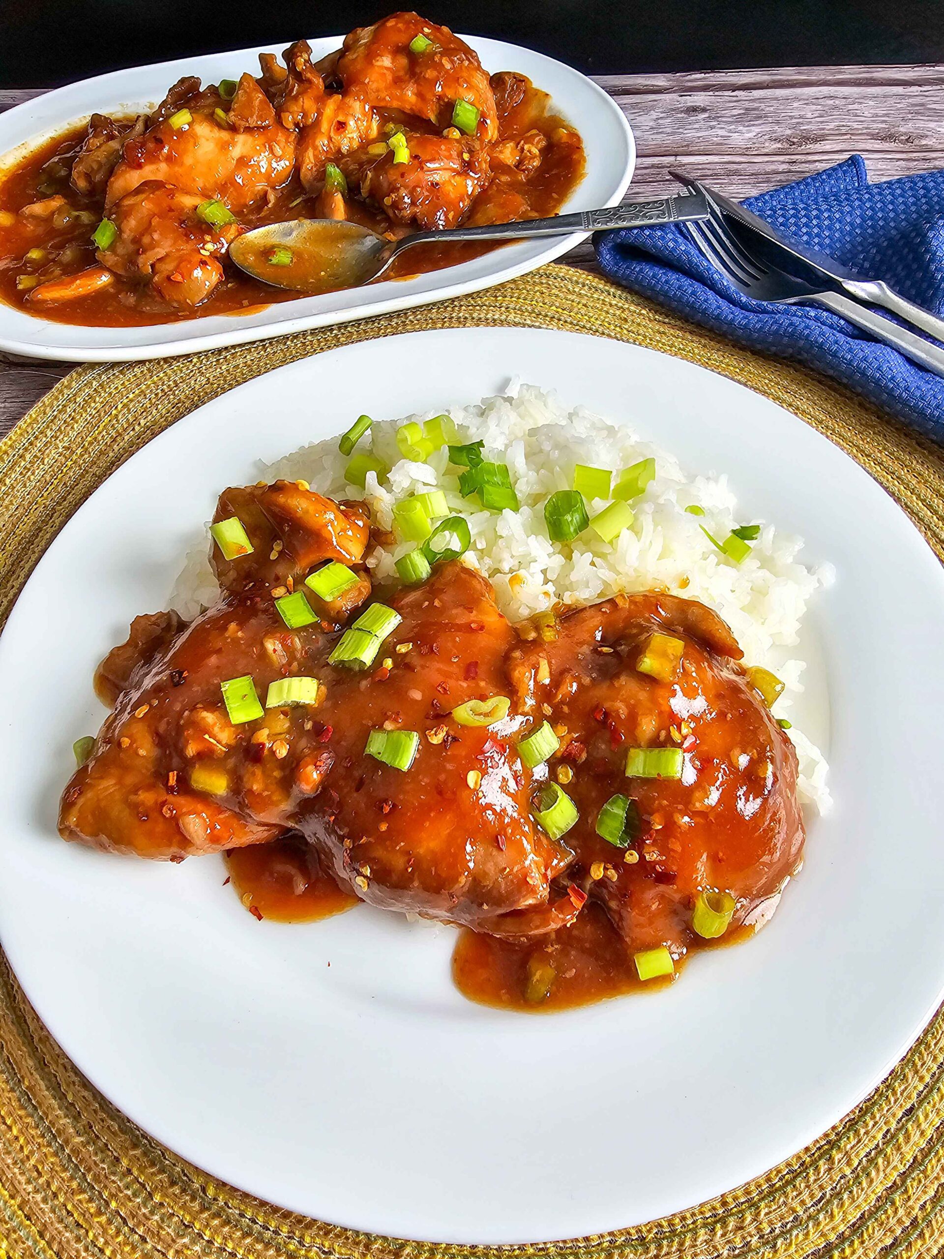  crockpot honey garlic chicken thighs garnished with sesame seeds and green onions served over rice