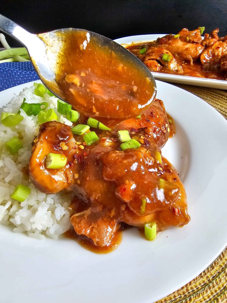 SPOONING THE THICKENED SAUCE OVER THE CROCKPOT COOKED CHICKEN THIGHS