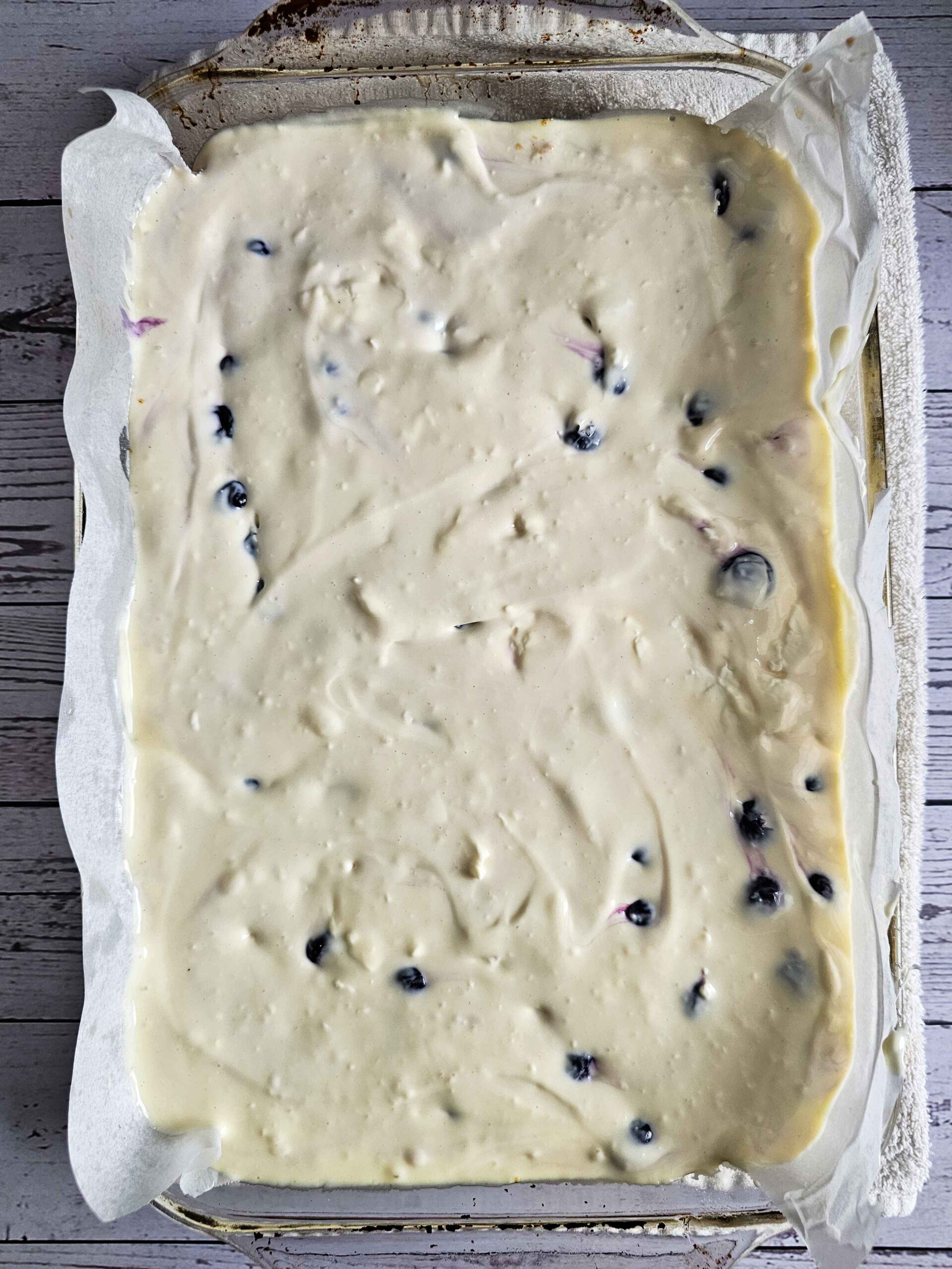 POUR THE BLUEBERRY FILLED CHEESECAKE BATTER ONTO THE PRE-BAKED GRAHAM CRACKER CRUST