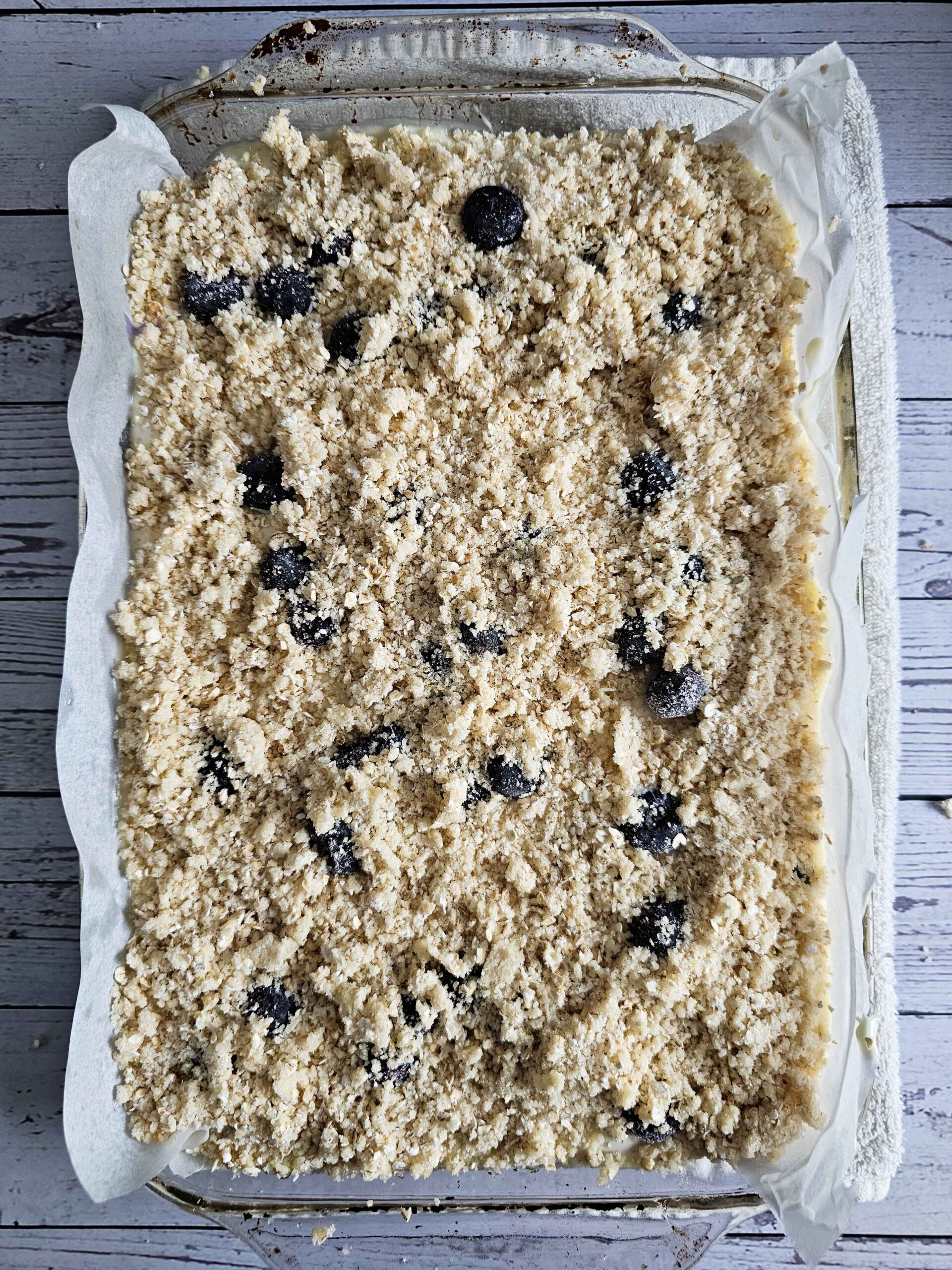 ADD THE CRUMBLE TOPPING AND THE REMAINING 1/2 CUP OF BLUEBERRIES ON TOP OF THE CHEESECAKE BATTER