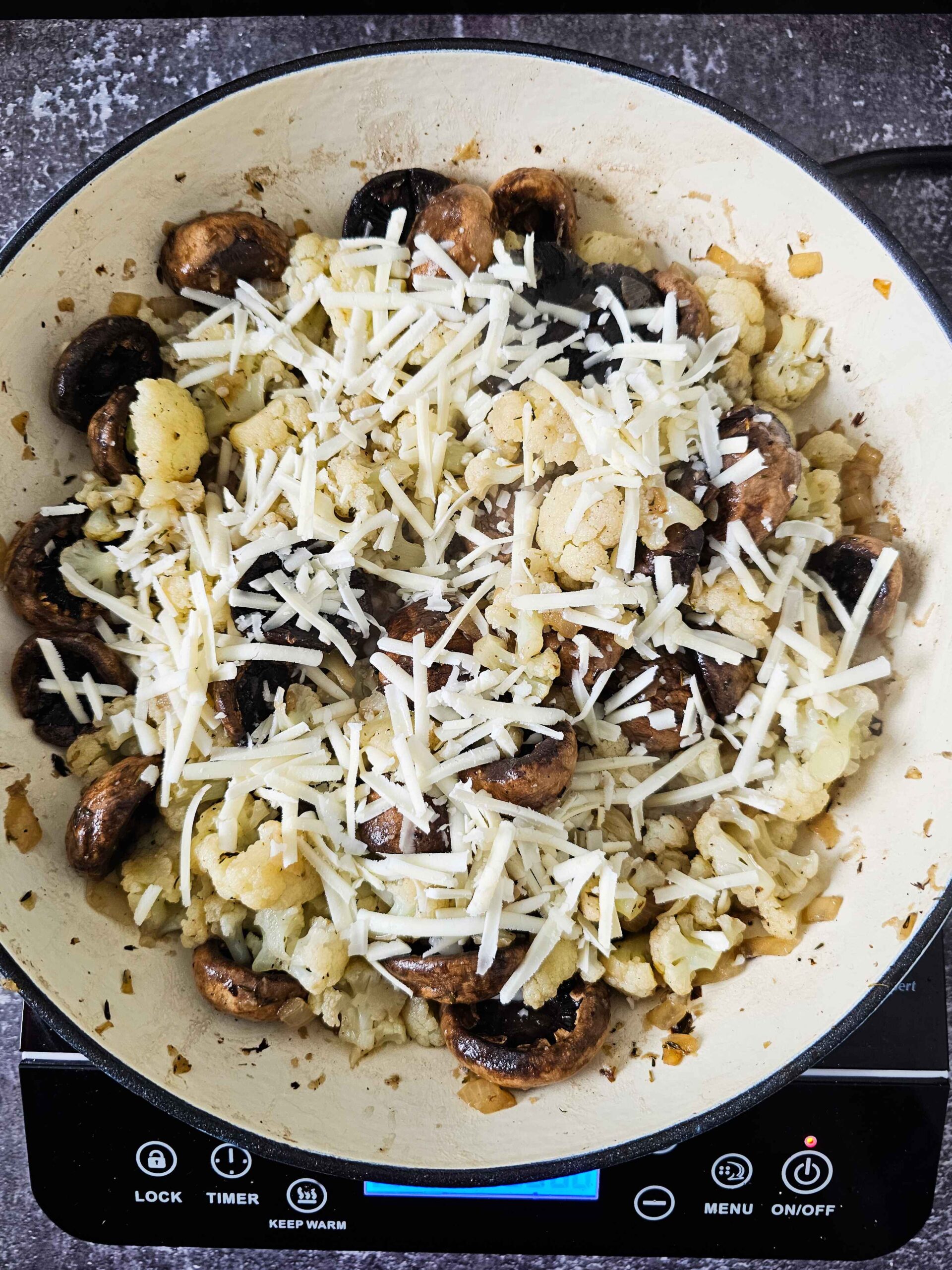 ADD THE MUSHROOMS, STEAMED CAULIFLOWER AND PARMESAN CHEESE TO SKILLET