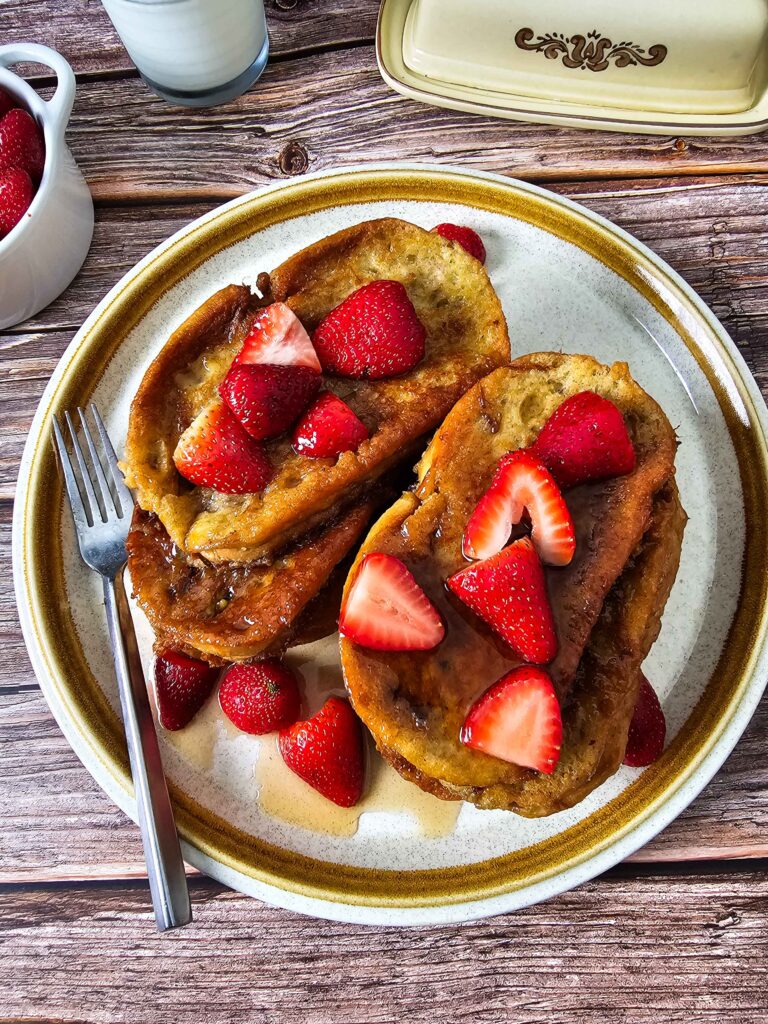 TOP VIEW OF STACKED FRENCH TOAST WITH MAPLE SYRUP AND STRAWBERRIES