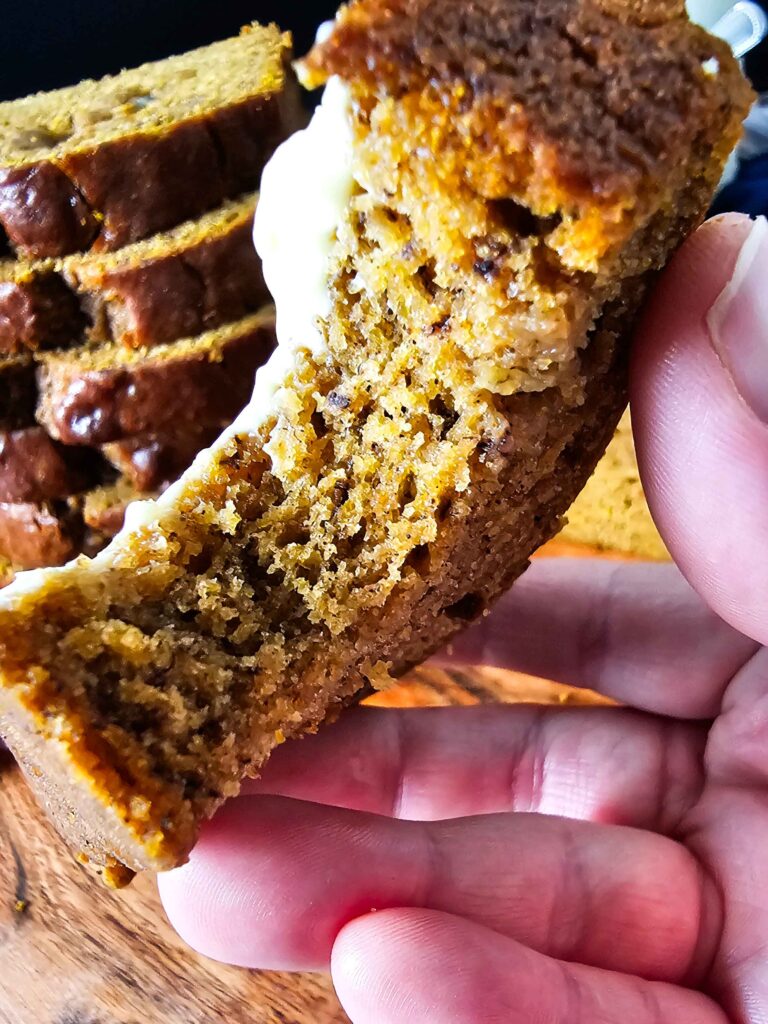 BIG BITE BEING TAKEN FROM A SLICE OF PUMPKIN BANANA BREAD