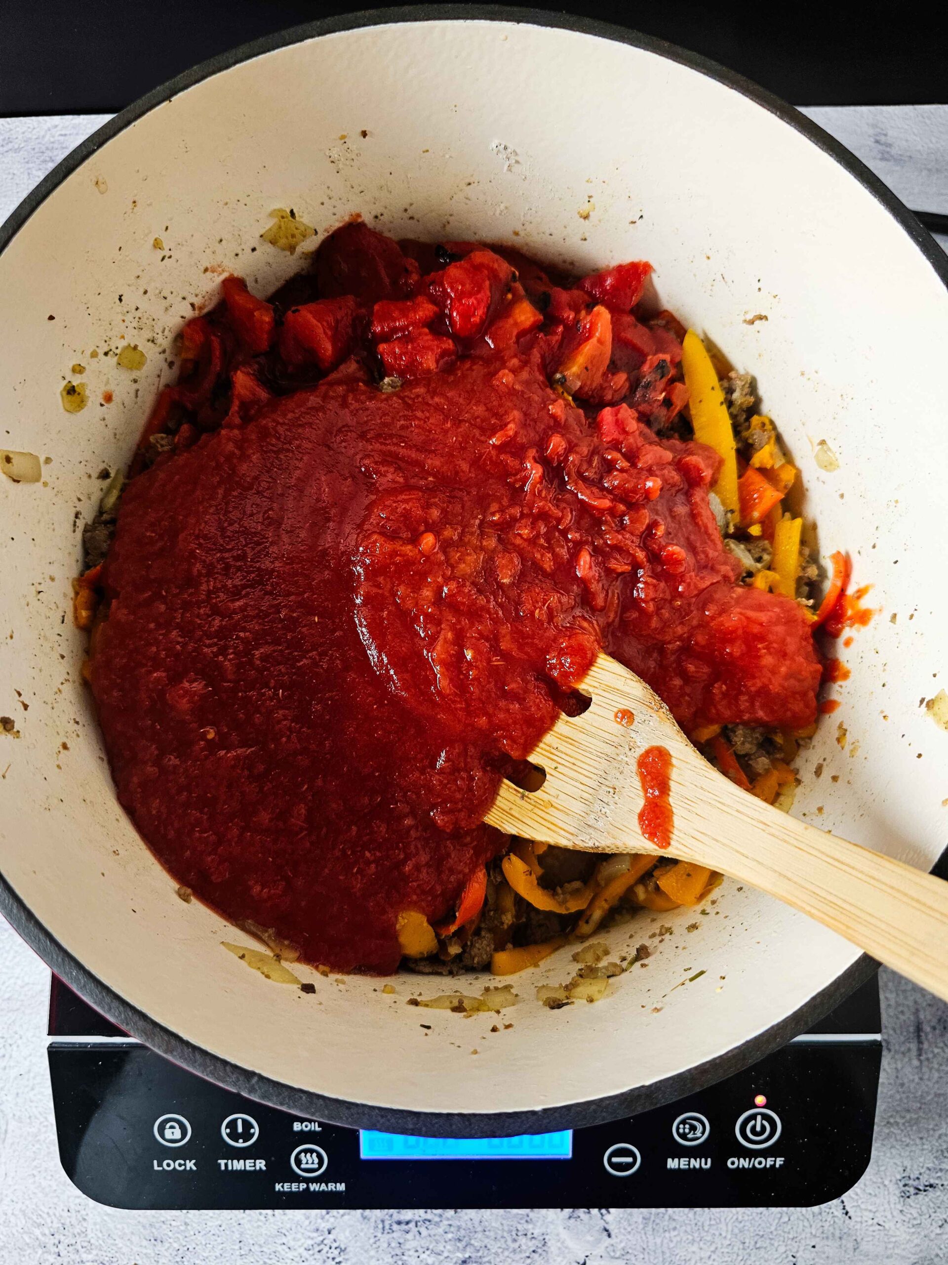 ADD THE TOMATOES AND BEEF BROTH TO THE DUTCH OVEN