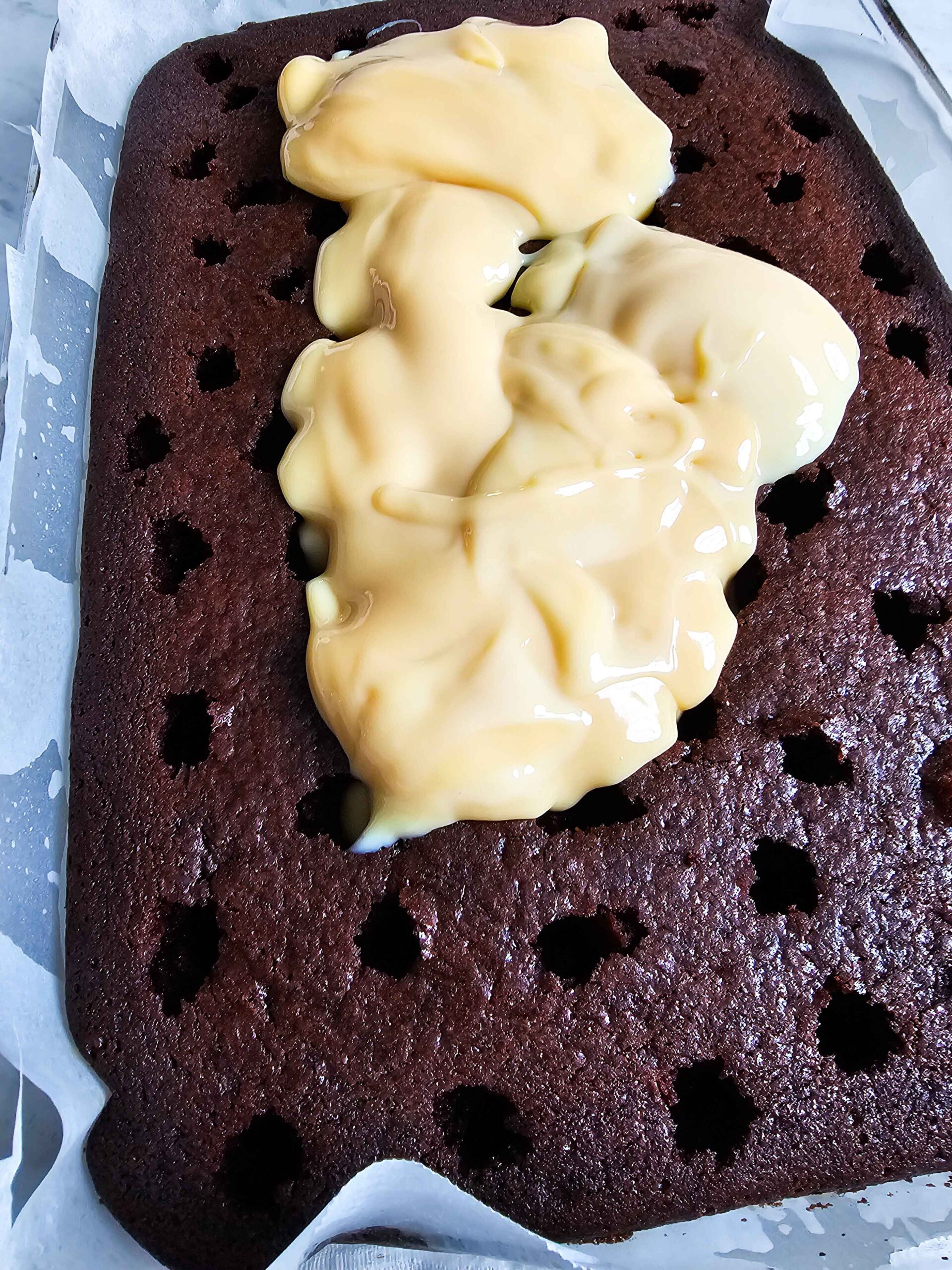 POUR THE SWEETENED CONDENSED MILK OVER THE POKED CHOCOLATE CAKE