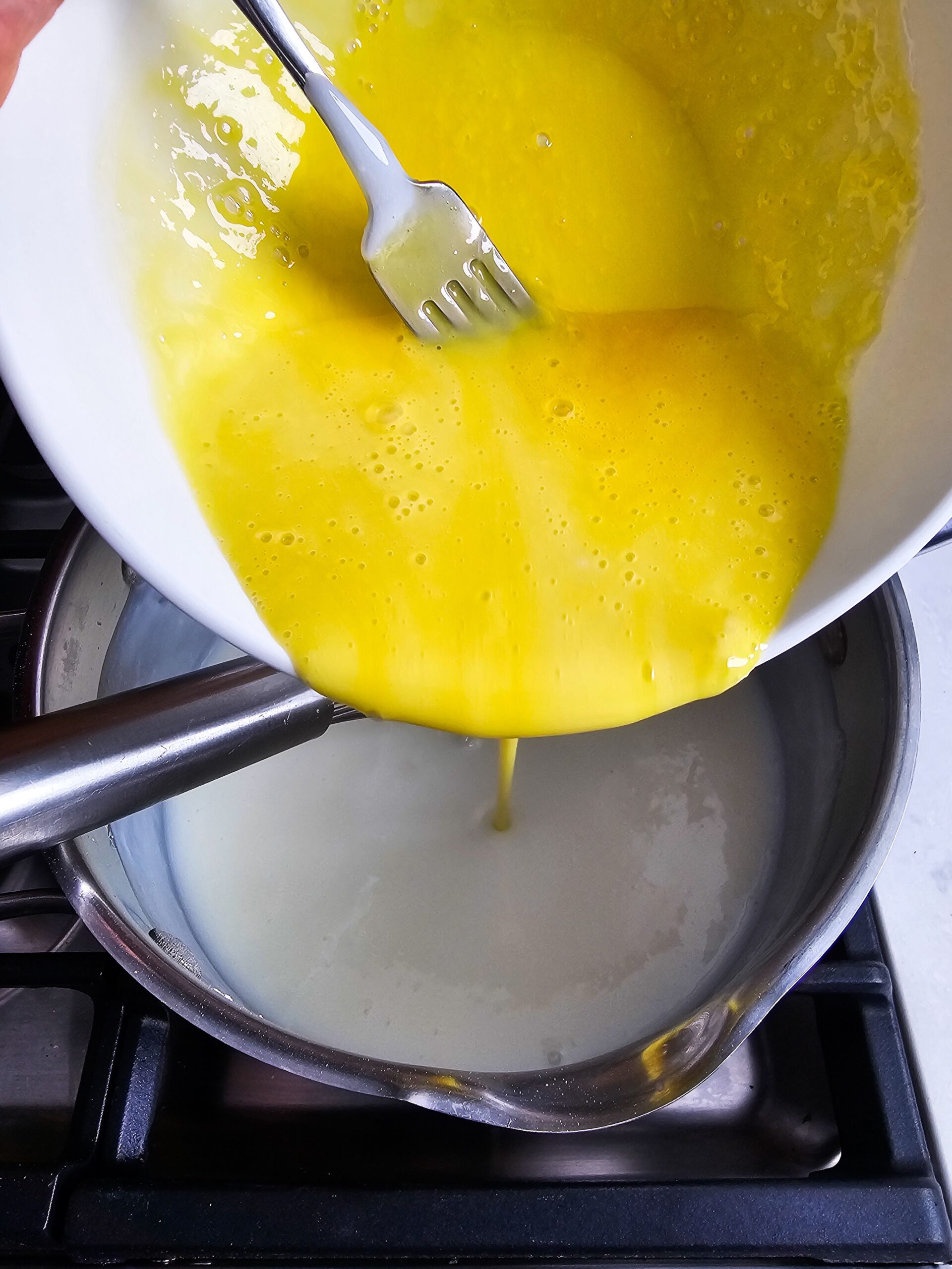 ADD THE TEMPERED EGGS TO THE MILK MIXTURE AND WHISK UNTIL SMOOTH